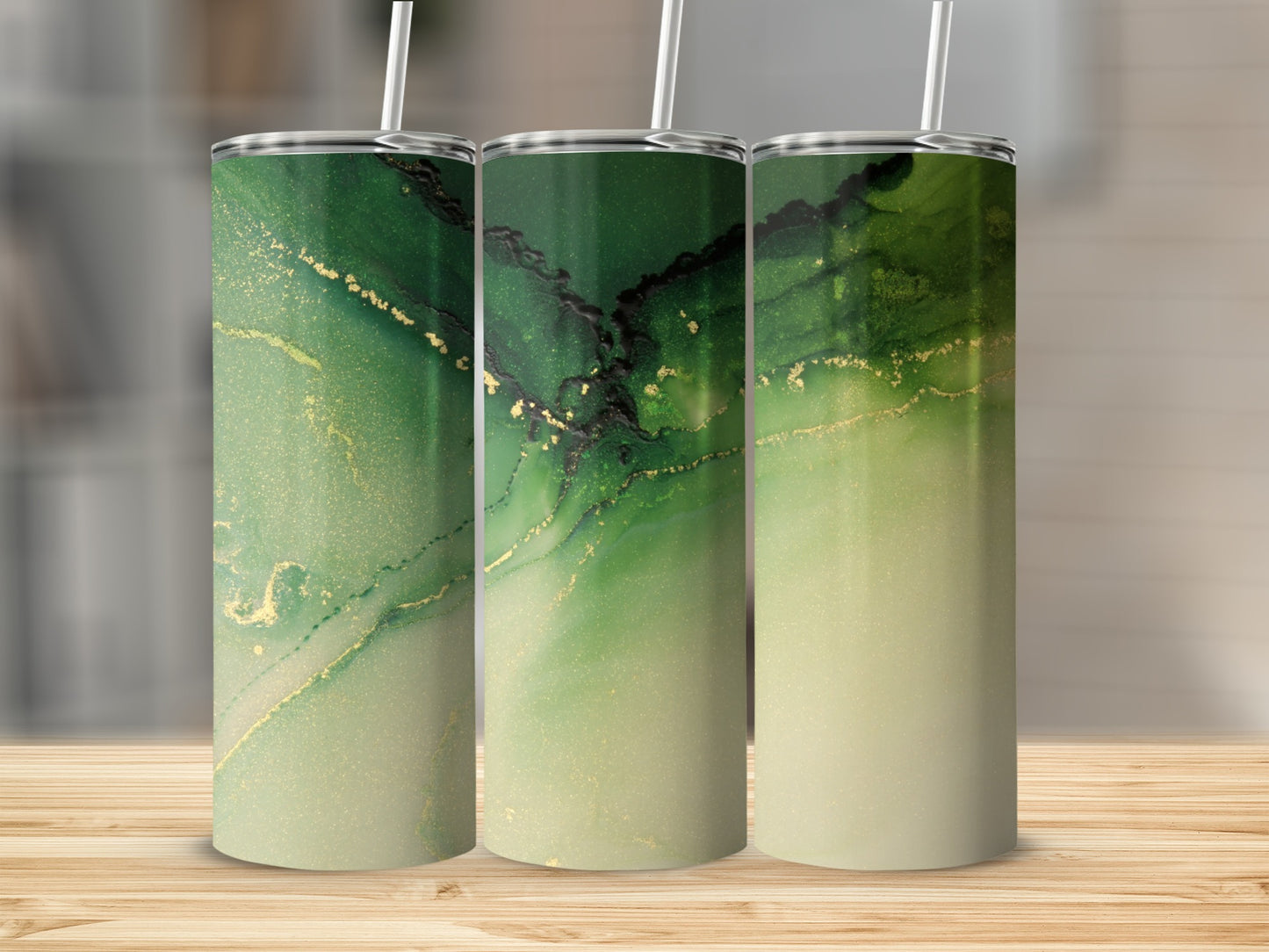 Three green and gold abstract pattern tumblers on a wooden surface.