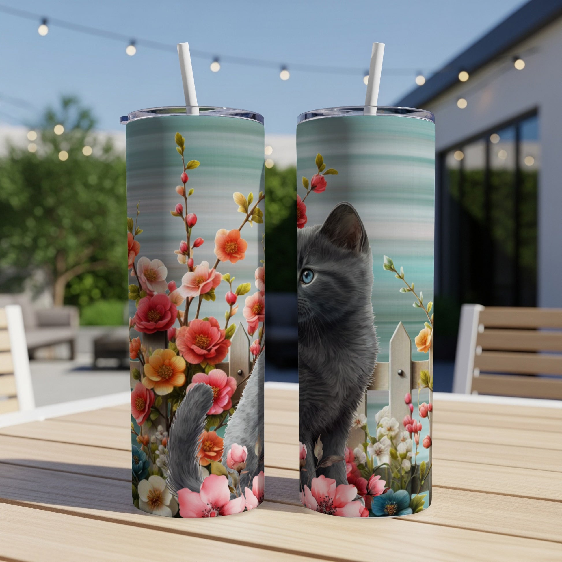Gray kitten peeking over fence surrounded by pink and orange blossoms.