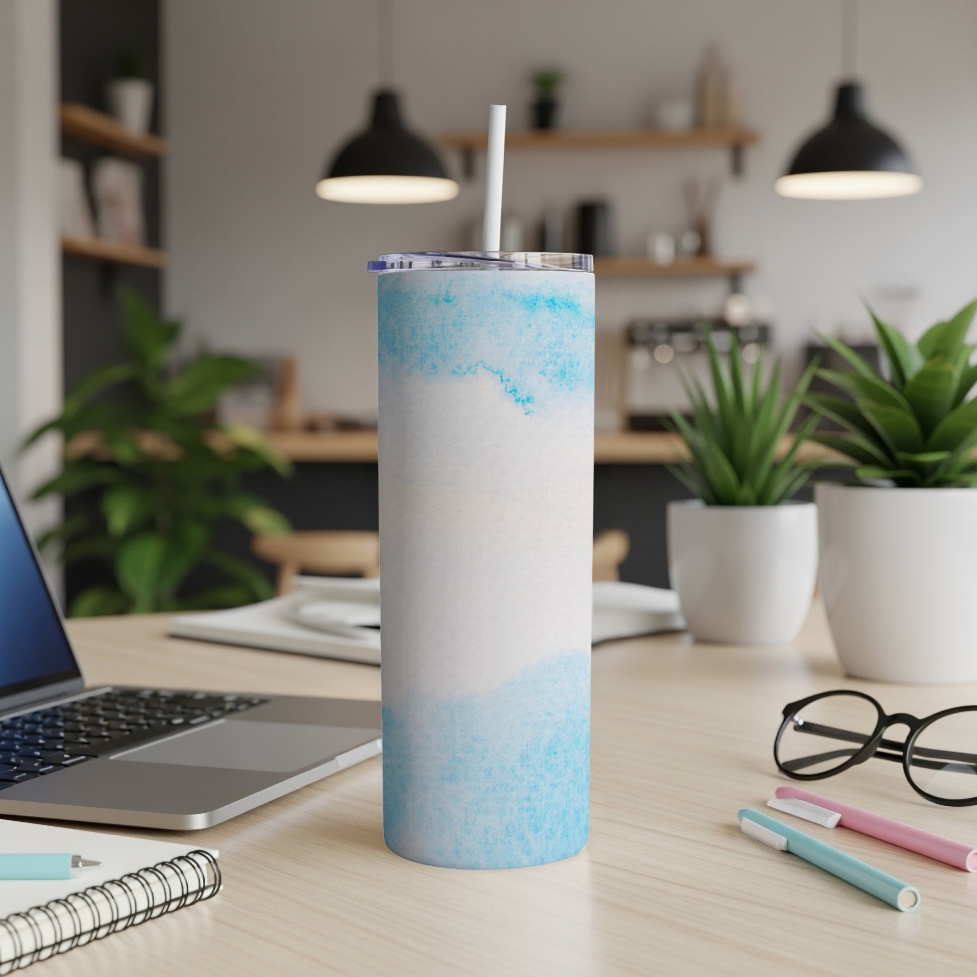 White and blue watercolor patterned tumbler with straw on desk.
