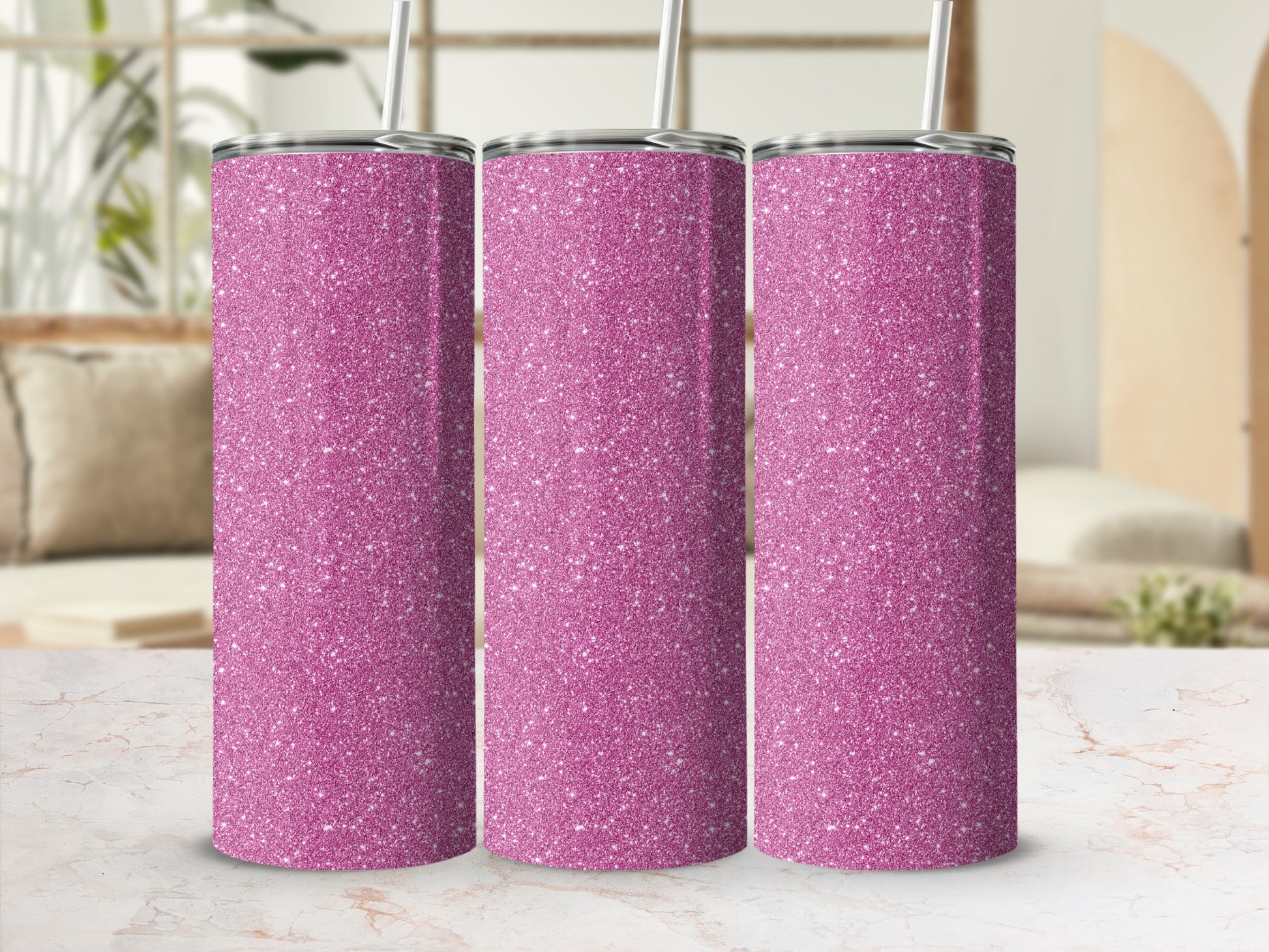 Three pink glitter tumblers with straws on a marble surface.