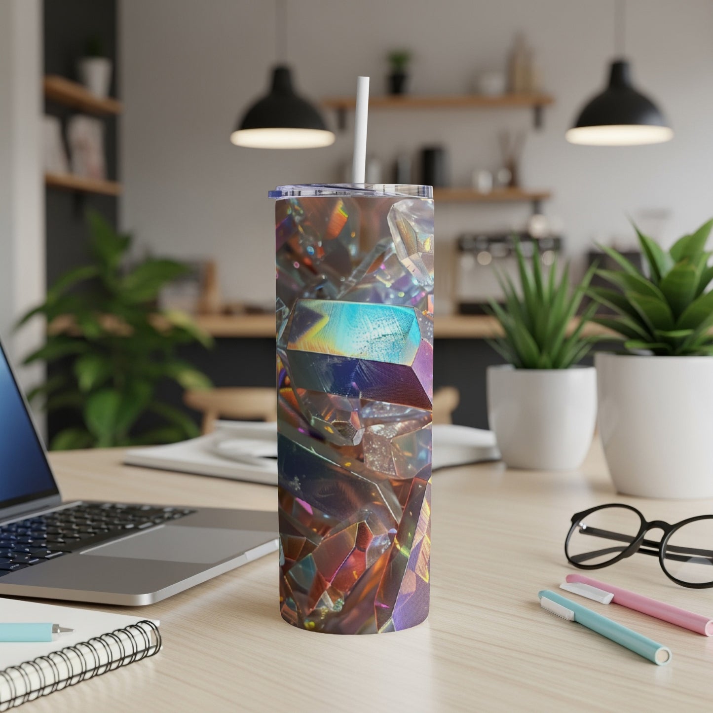 Tumbler with iridescent crystal design on a desk with laptop and pens.