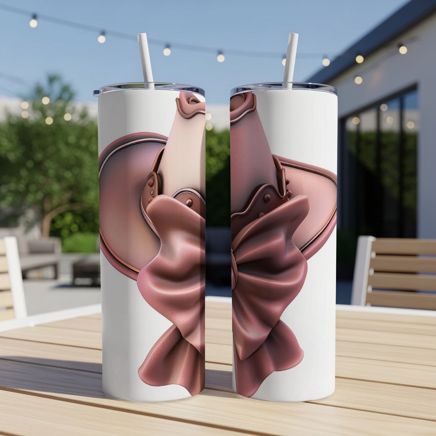 Two white tumblers with rose gold bow designs on an outdoor table.