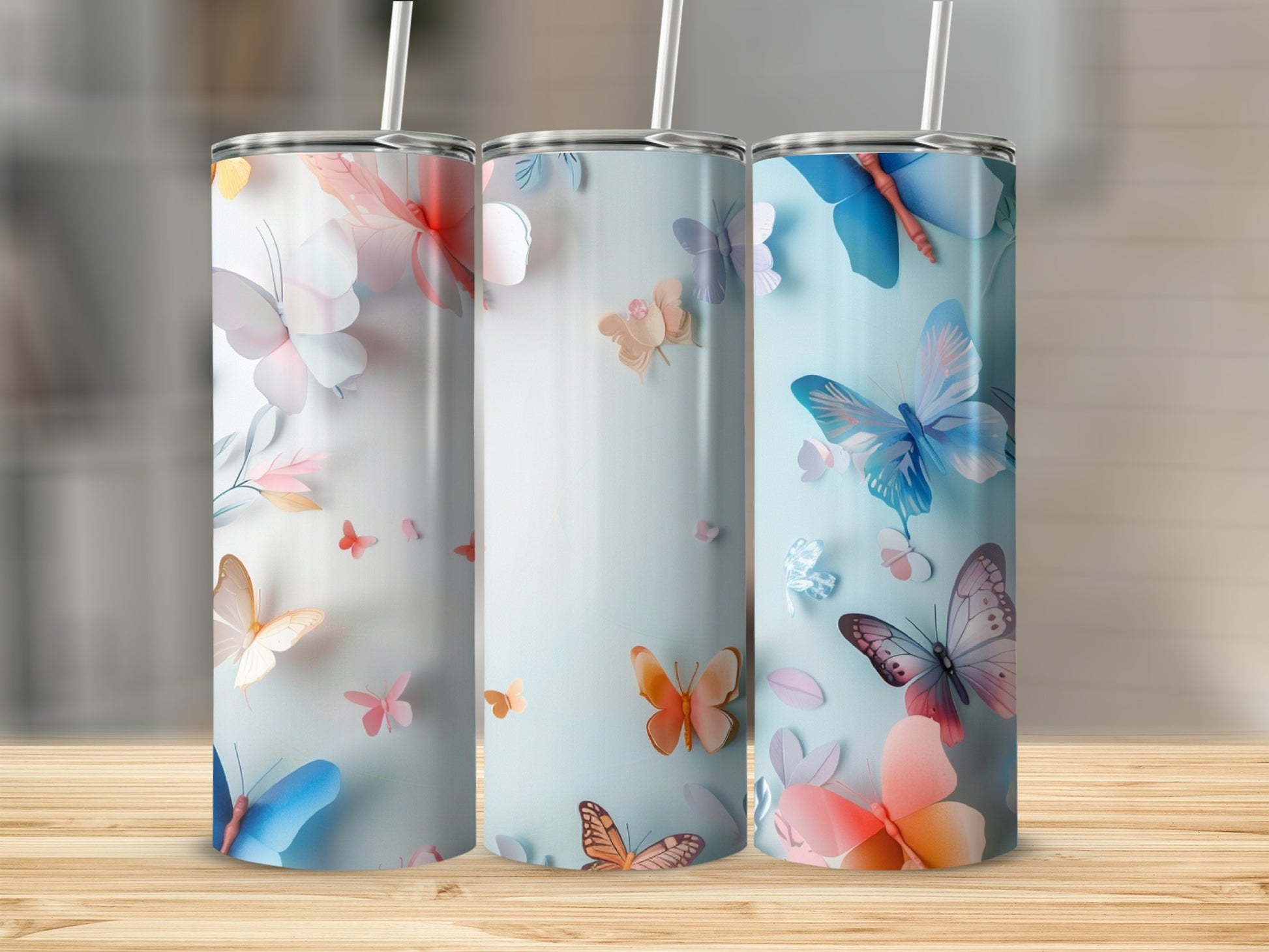 Three tumblers with butterfly designs on a wooden surface.