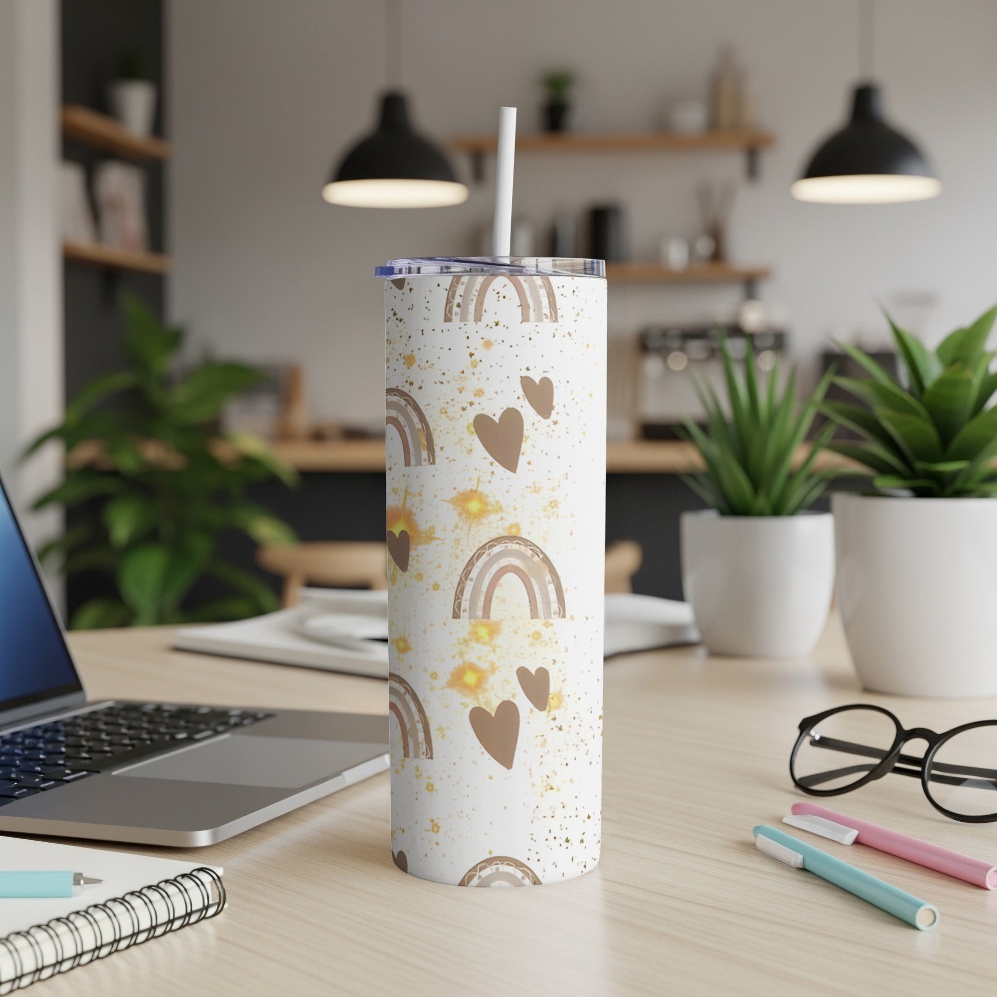 White tumbler with gold rainbows and hearts, straw inserted.