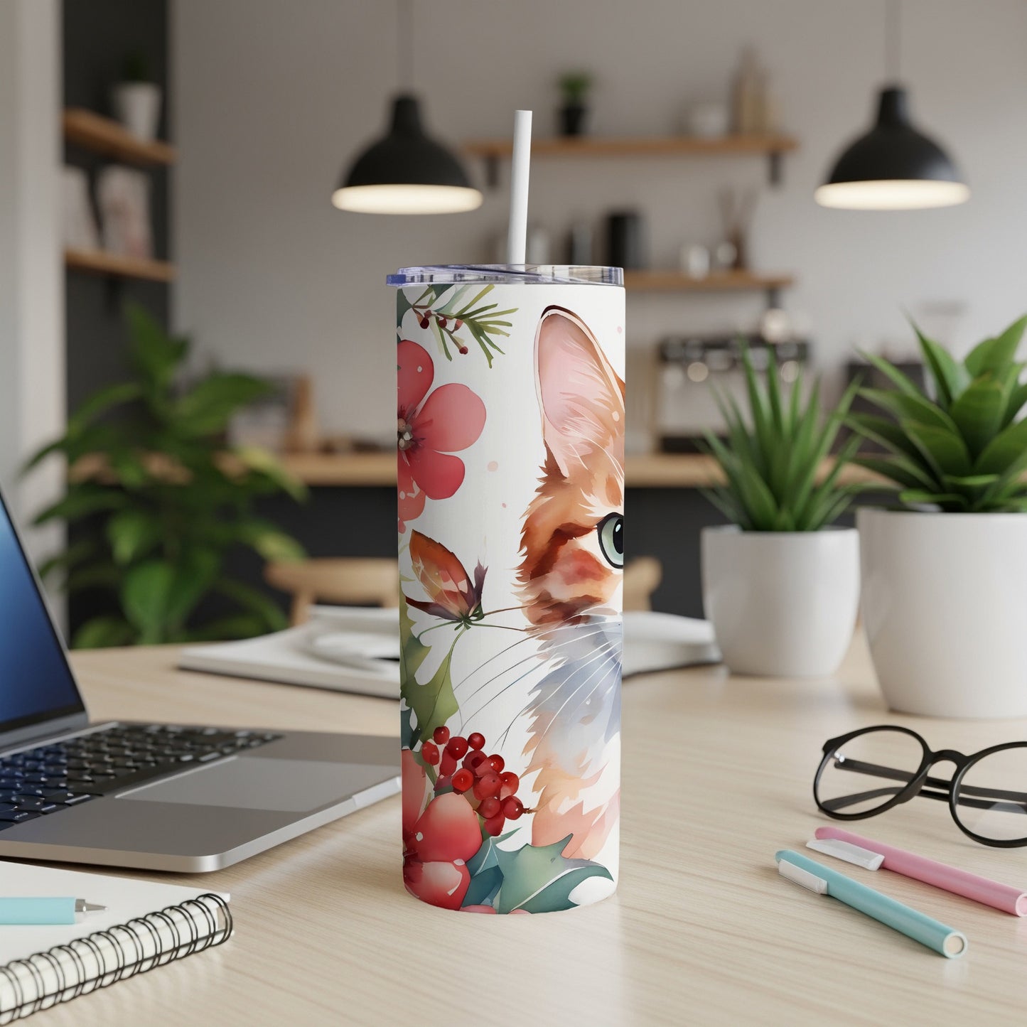 White tumbler with a watercolor cat face and floral design, beside a laptop.