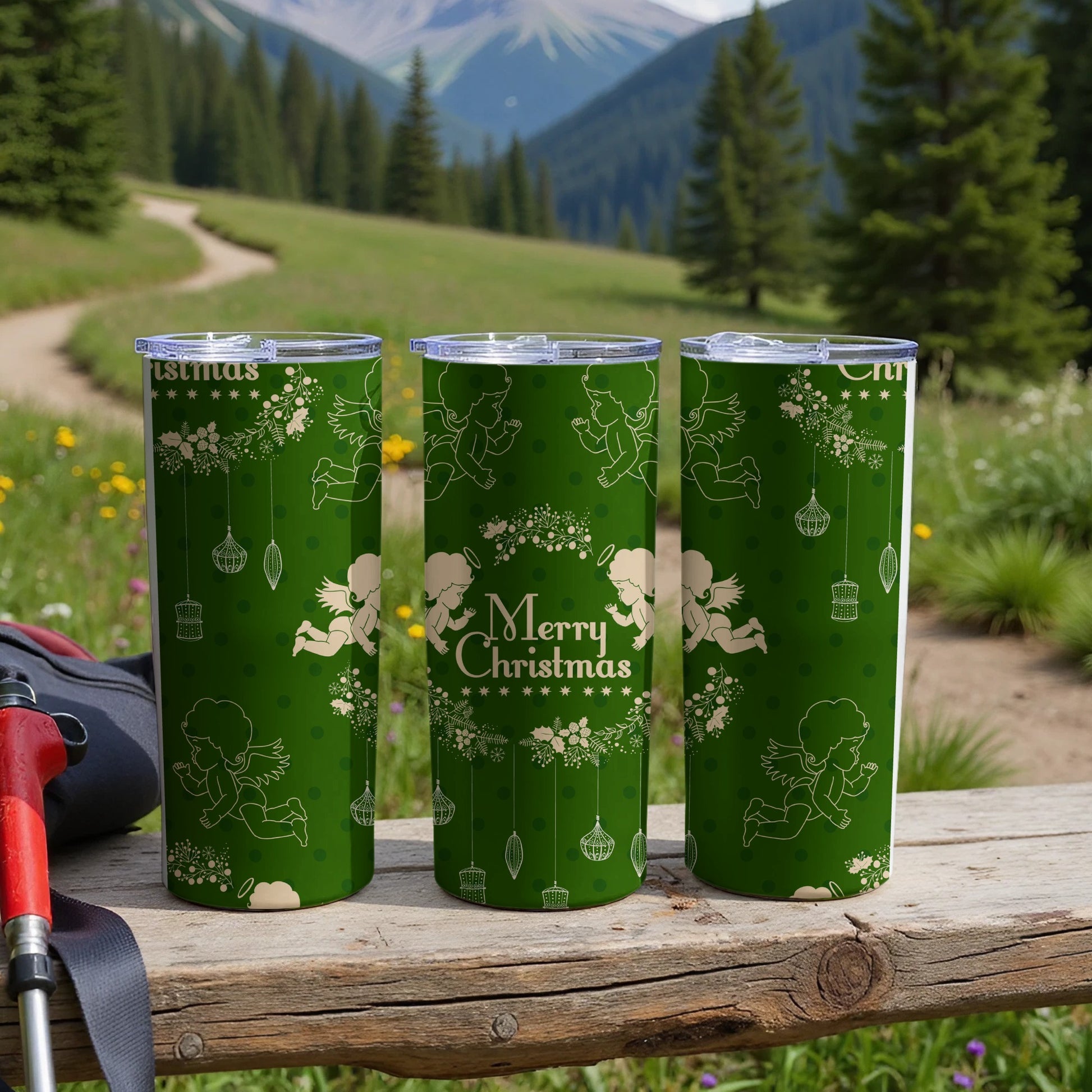 Three green tumblers with "Merry Christmas" and cherubs in a mountain landscape.