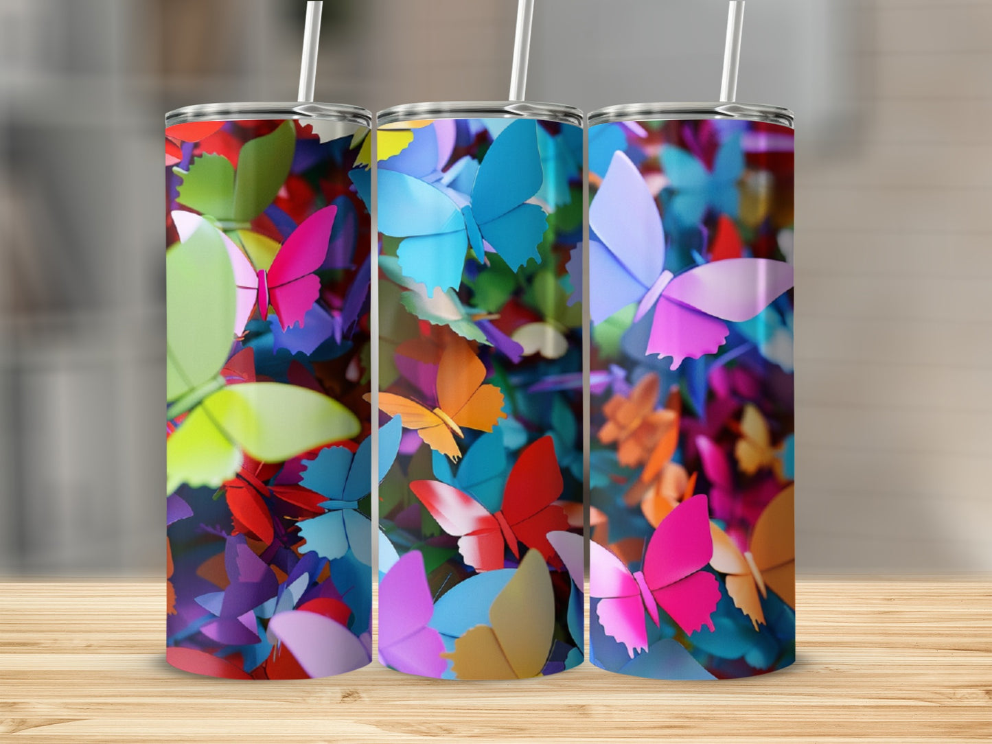 Three tumblers with colorful butterfly patterns on a wooden surface.