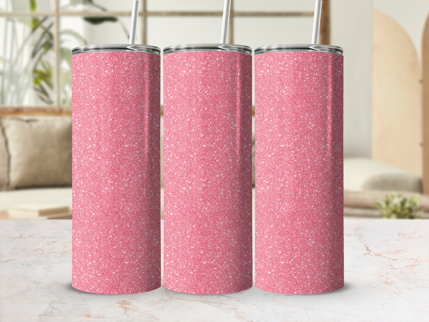 Three pink glitter tumblers with silver lids and straws displayed on a marble surface.