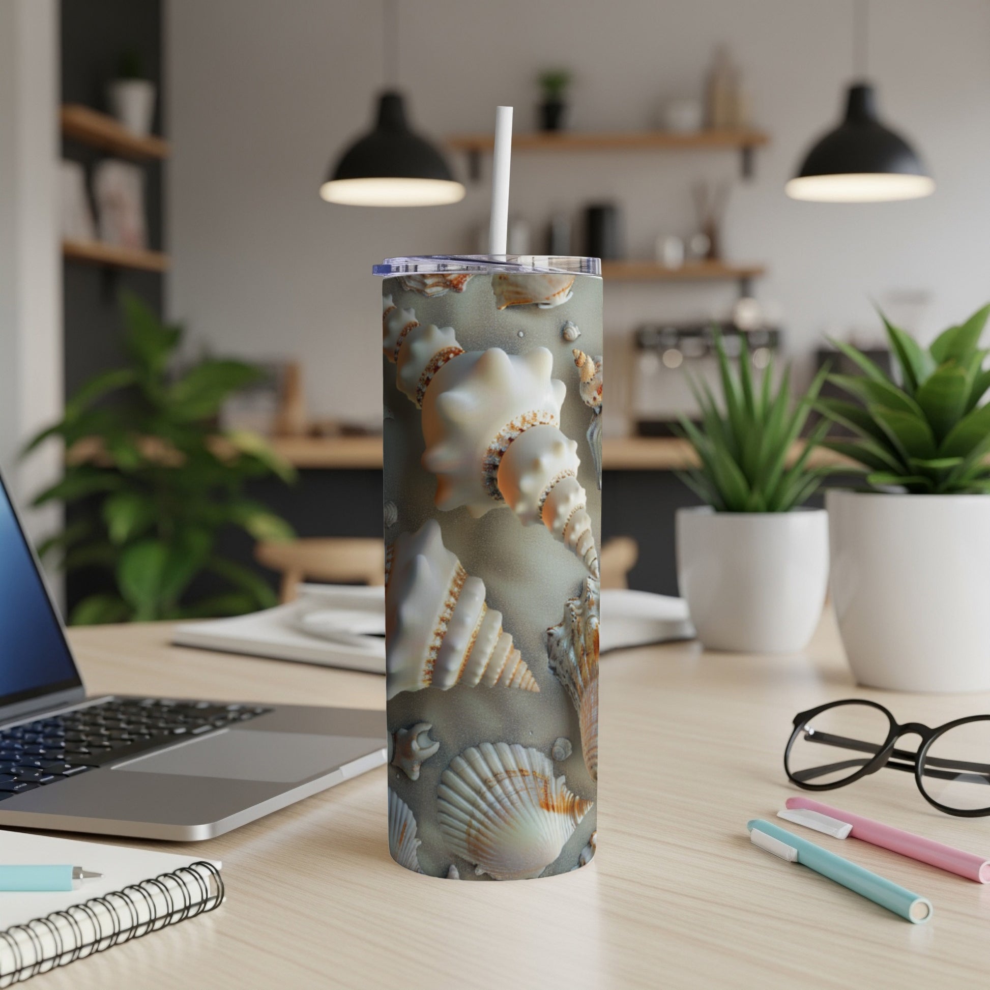 Tumbler with seashell pattern and beach sand background.