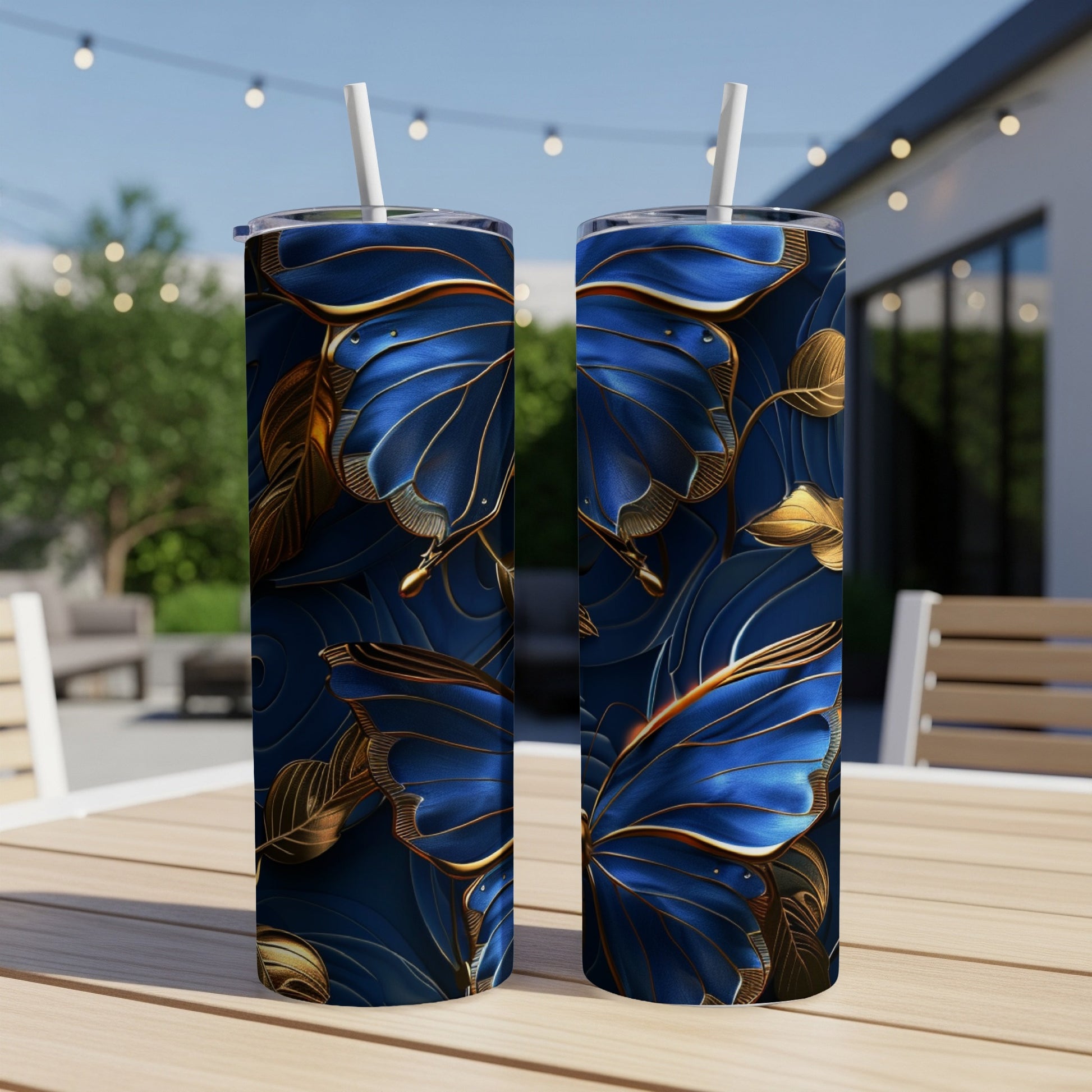 Two blue and gold butterfly tumblers with straws on a wooden table.
