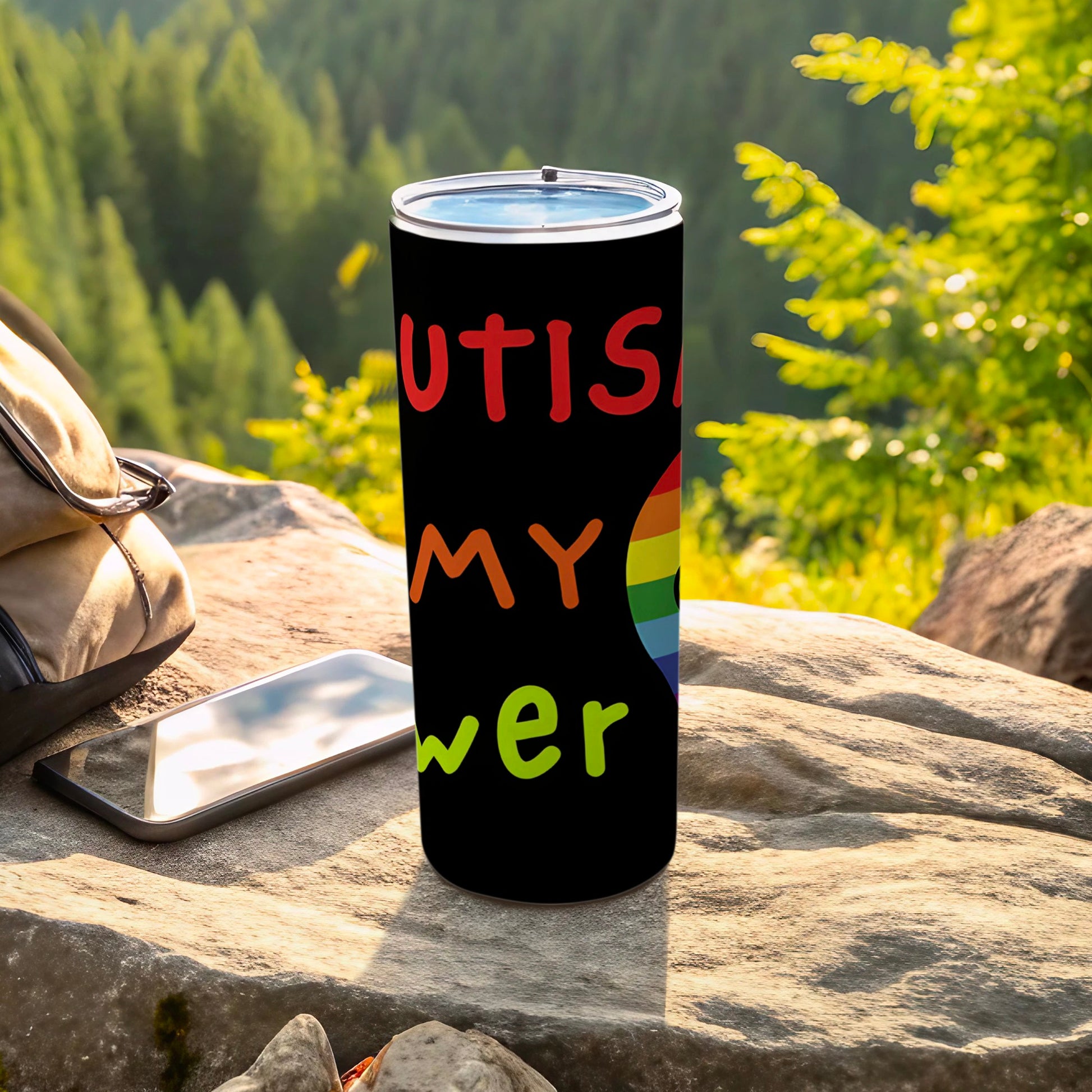 Black tumbler with "Autism is my superpower" in colorful lettering and rainbow.
