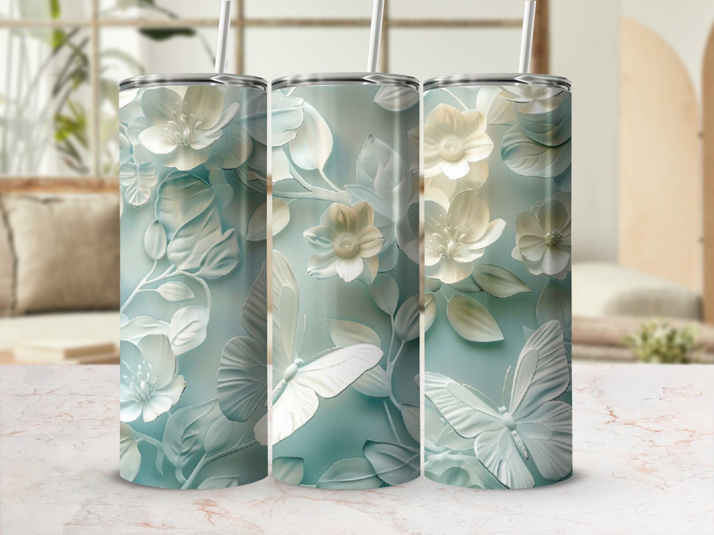 Three tumblers with a white floral and butterfly design on a light blue background.