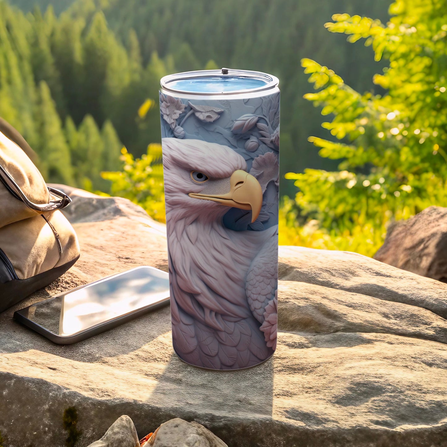 Eagle design on a stainless steel tumbler with phone and backpack outdoors.