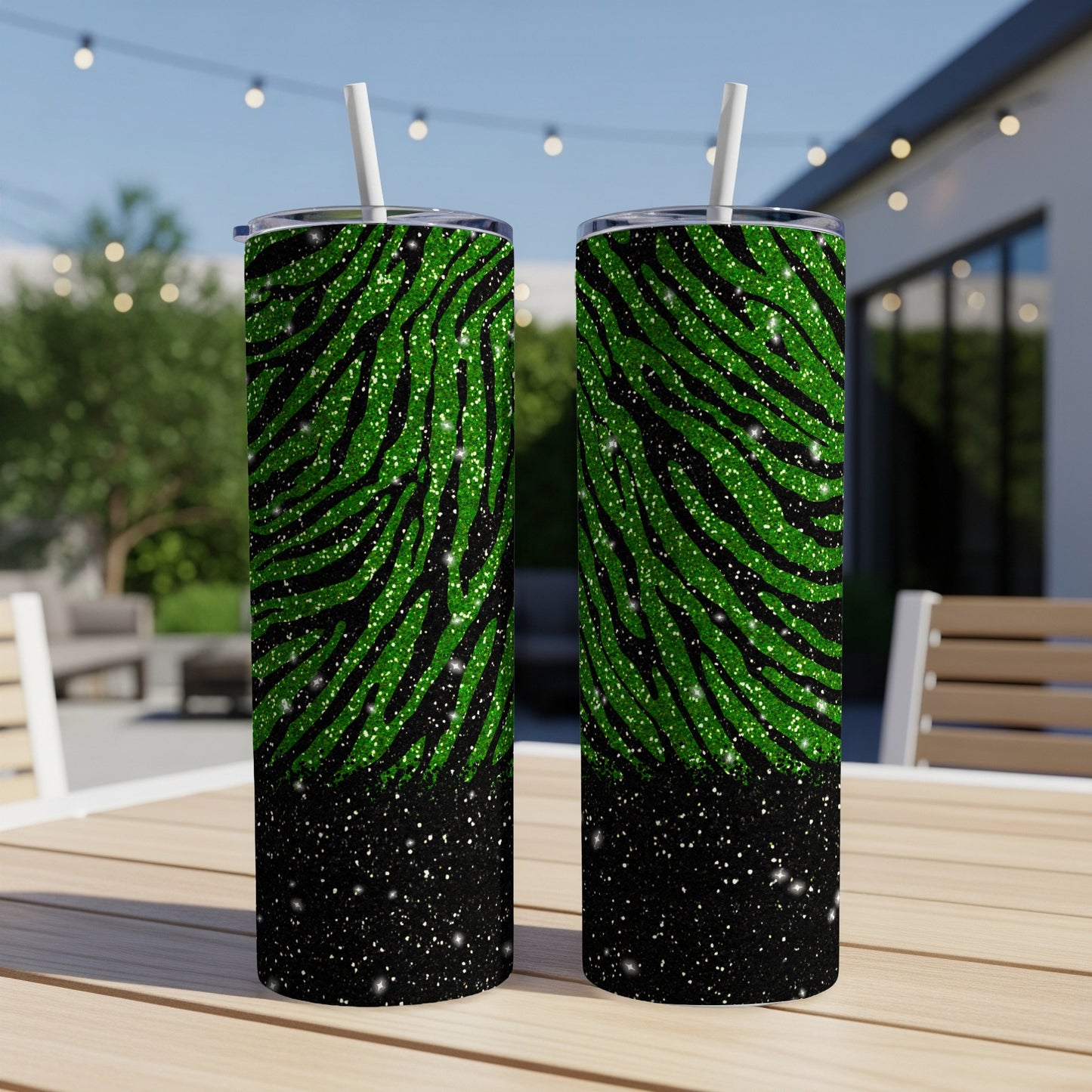 Two green glitter zebra print tumblers with white straws on a wooden table.