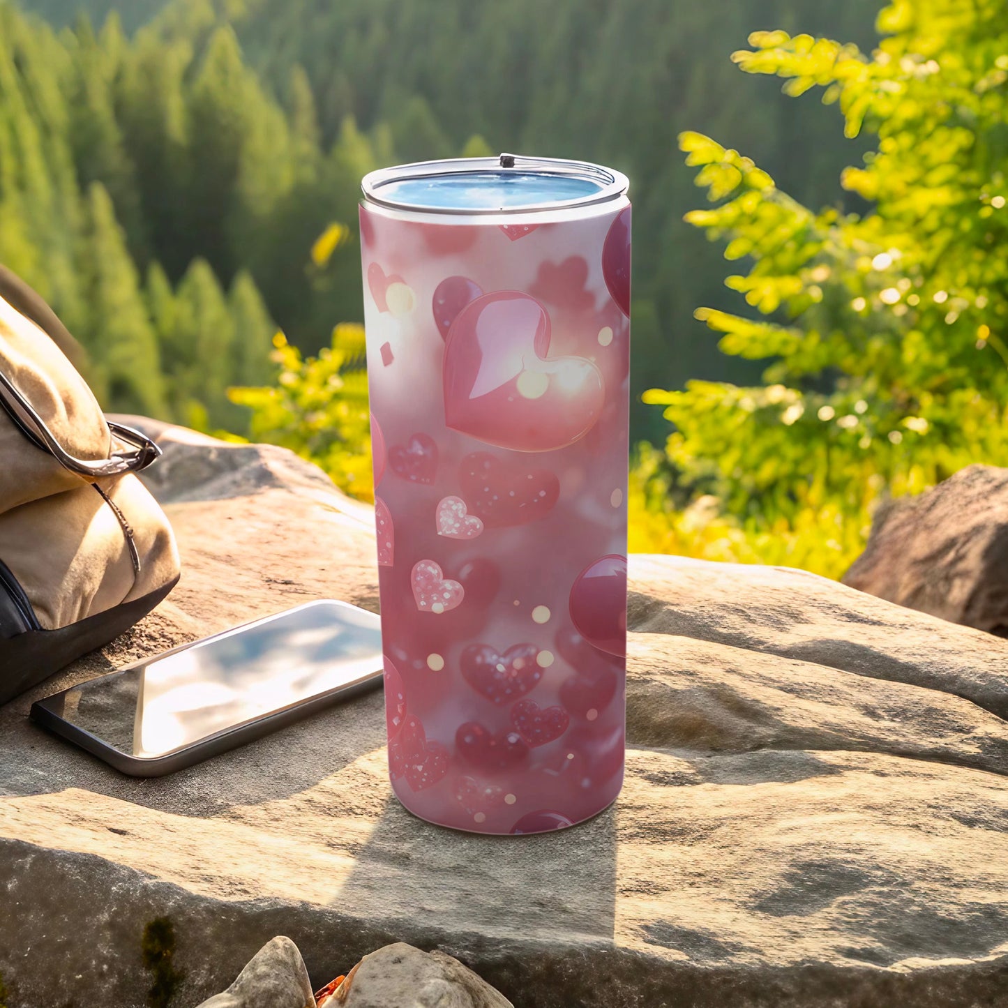 Pink hearts pattern on a tall, clear-lidded tumbler next to a phone.