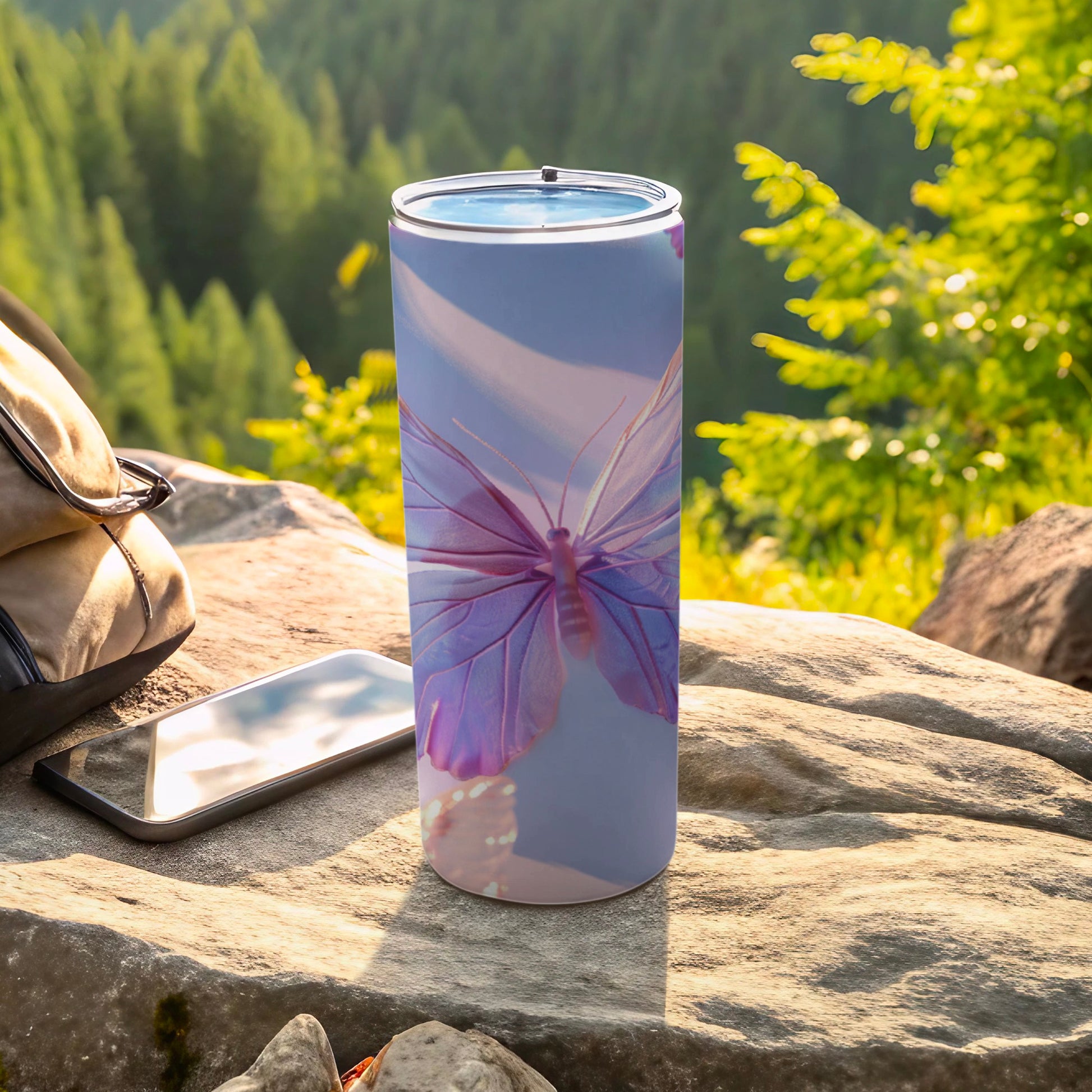 Purple butterfly on a blue-toned insulated tumbler next to a phone and bag.