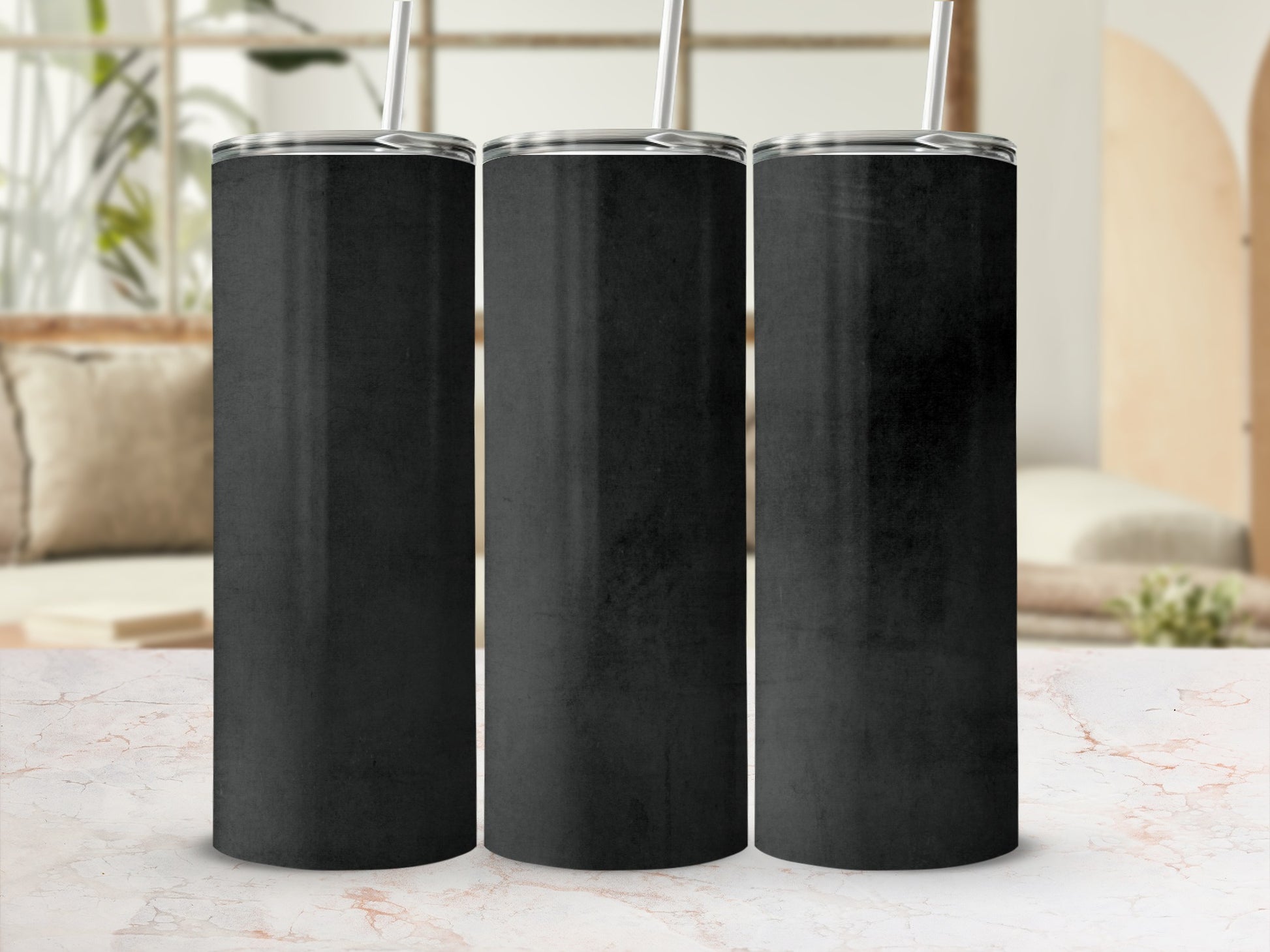 Three plain black tumblers with silver lids and straws stand in a row.