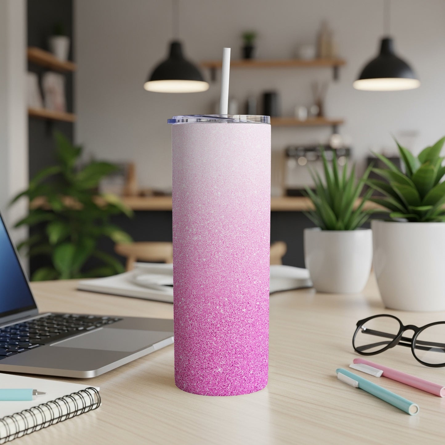 Pink glitter gradient skinny tumbler with straw on a desk.