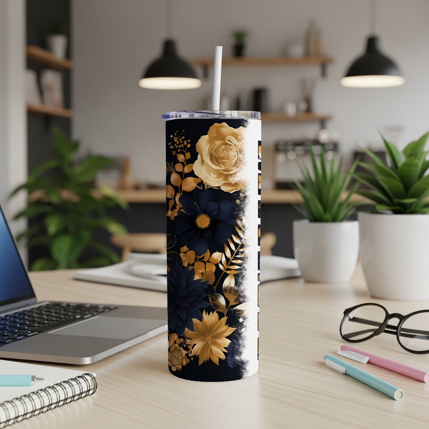 Black and gold floral tumbler with straw on desk.