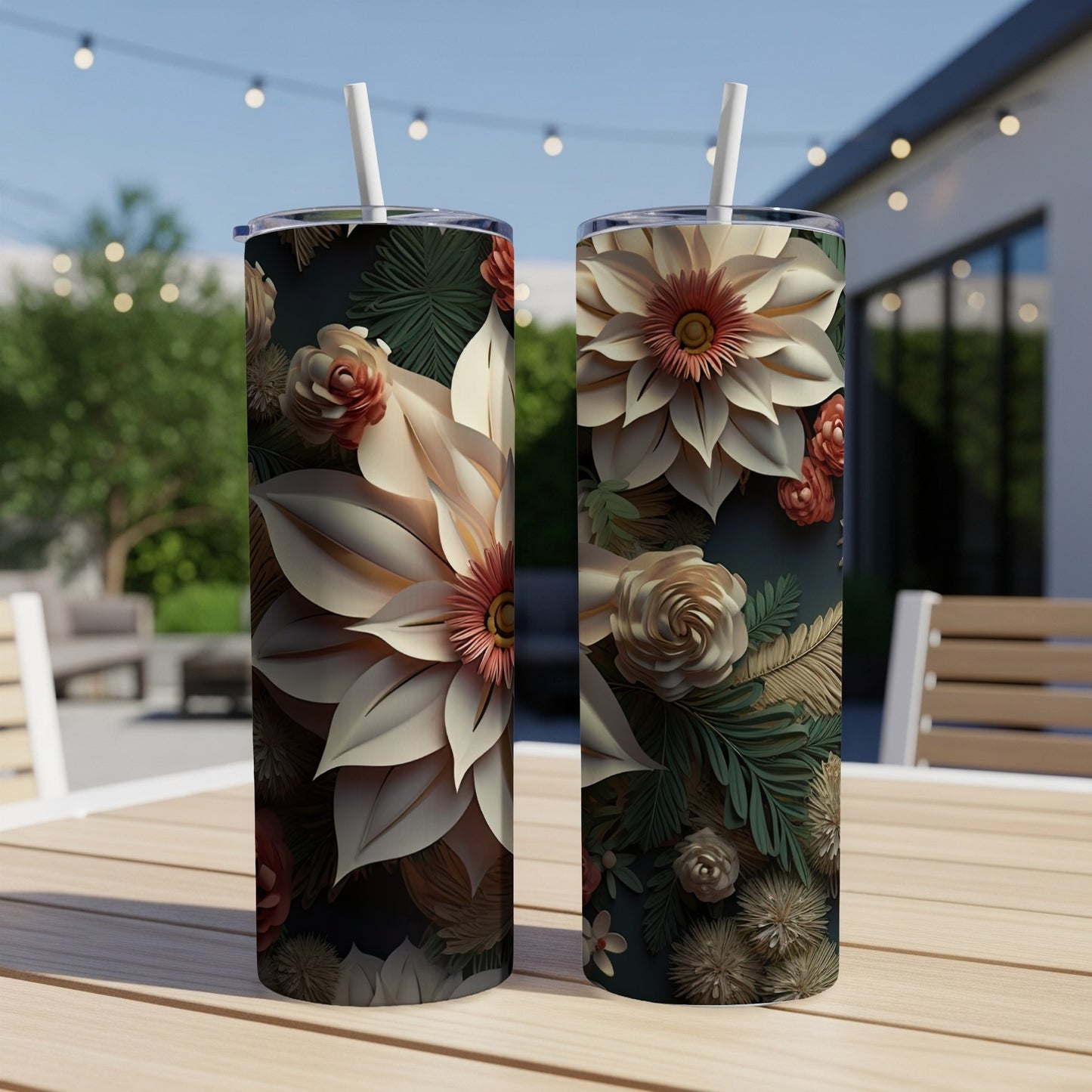 Two tall tumblers with a floral design sit on a table outdoors.