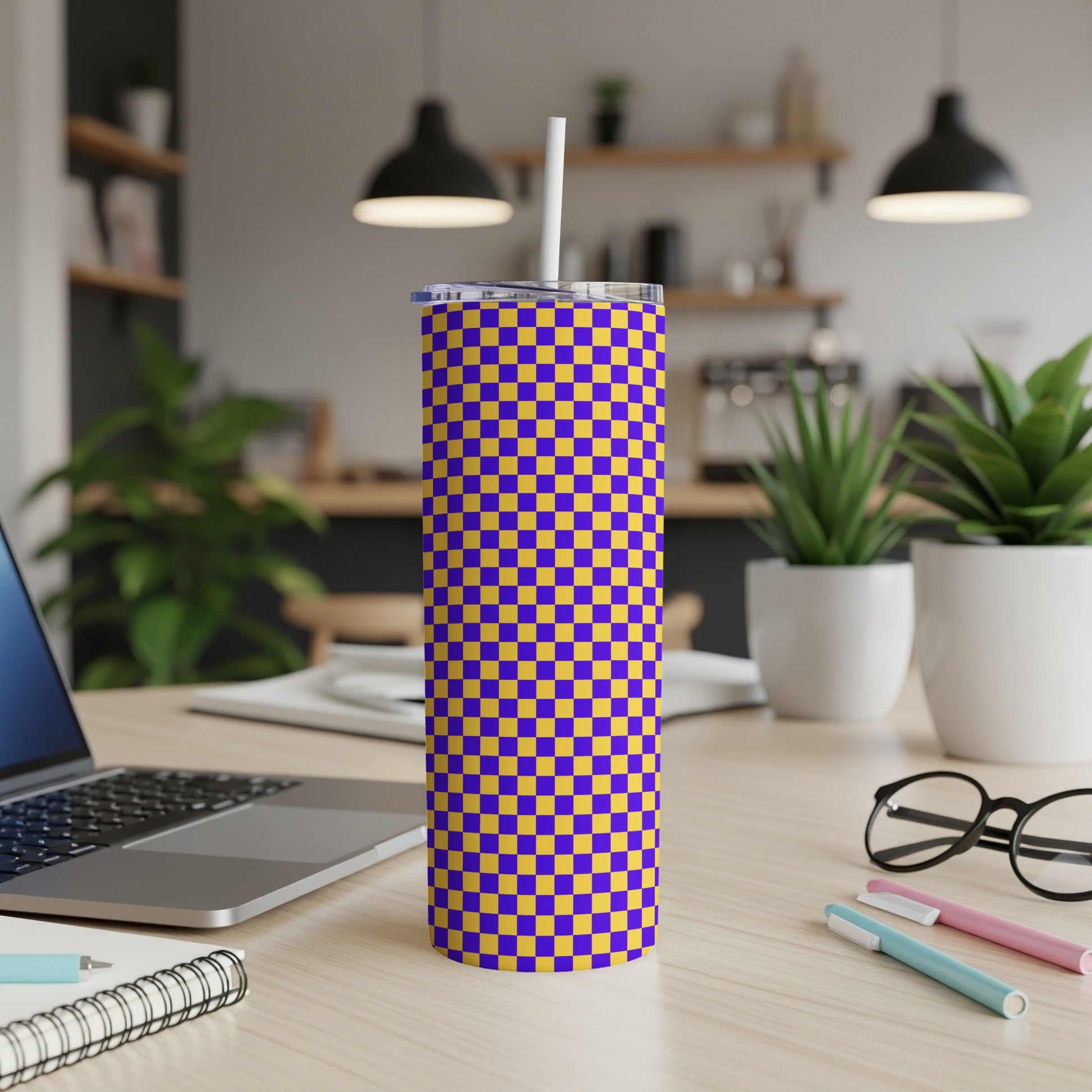 Purple and yellow checkerboard tumbler with white straw on desk.