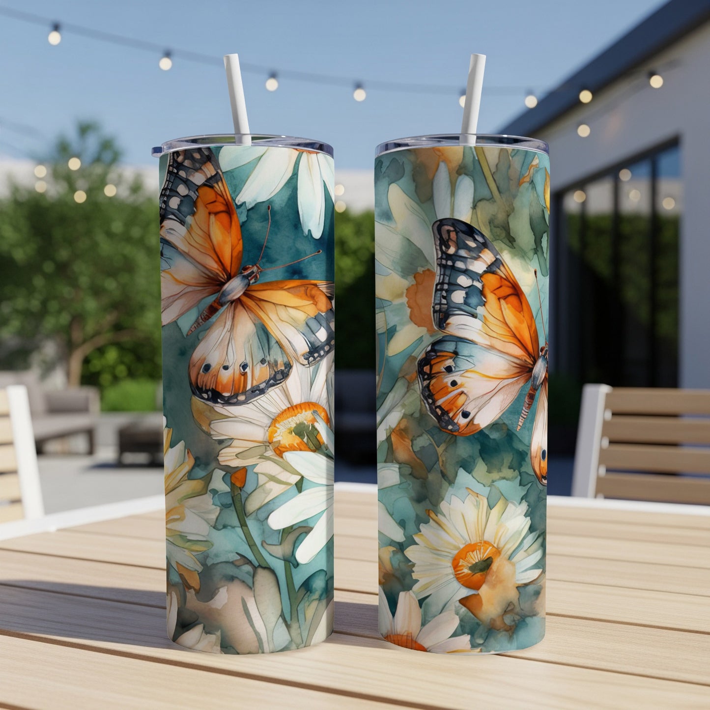 Two tumblers with monarch butterflies and daisies on a wooden table.