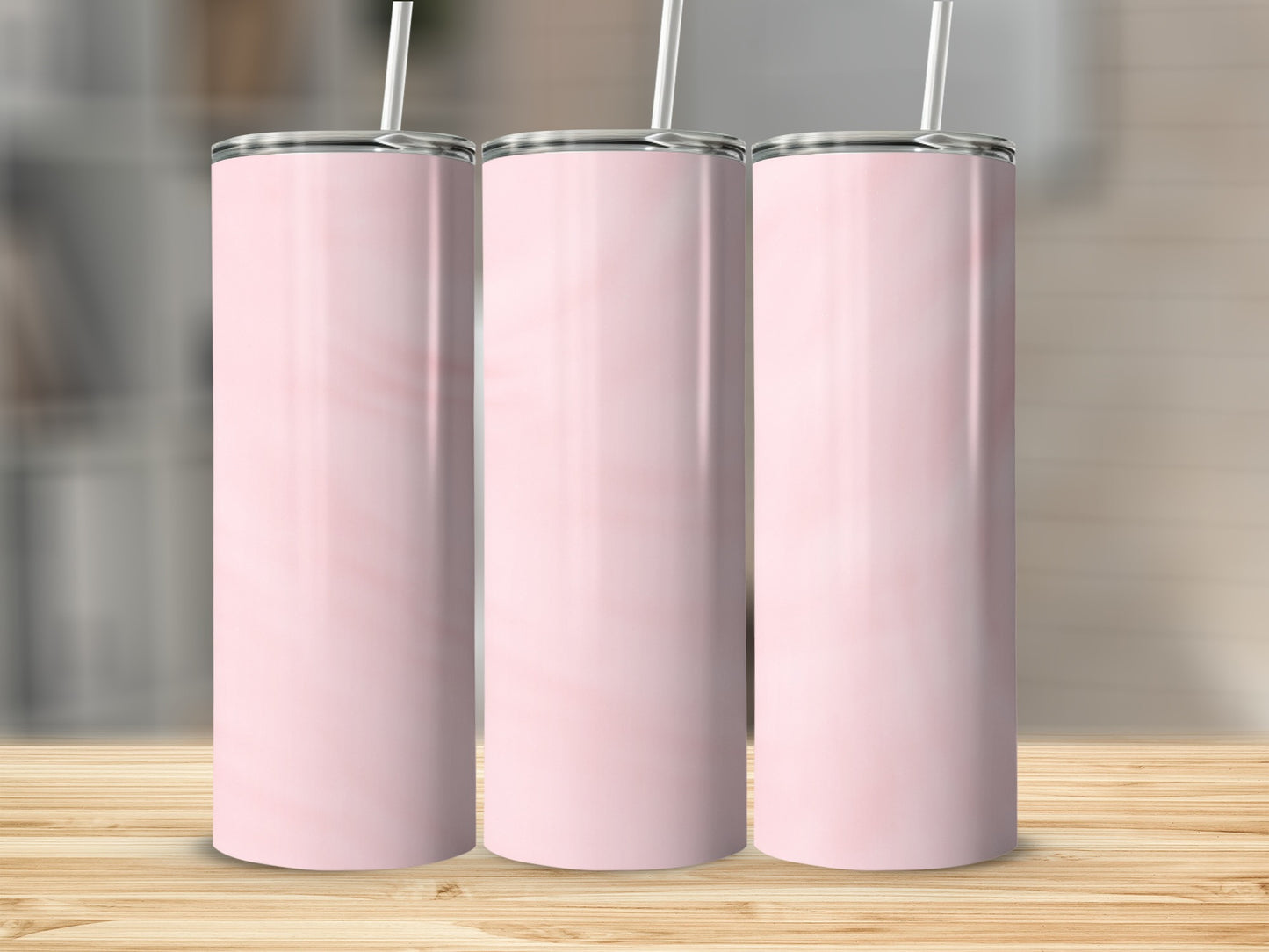 Three blank pink marble tumblers with white straws on a wooden surface.