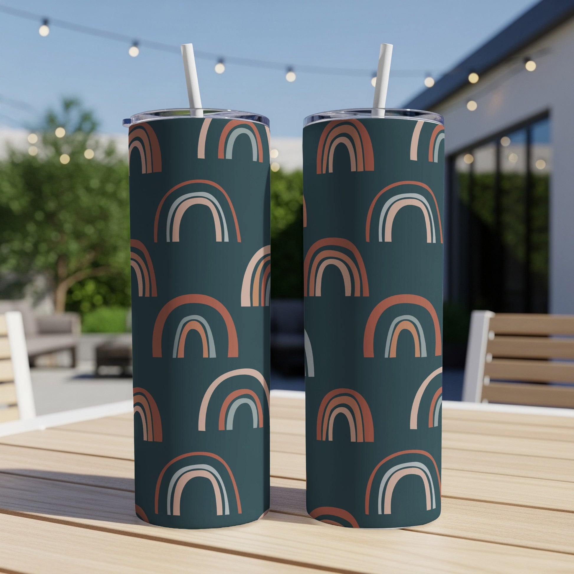 Two tumblers with a dark teal background and a repeating pattern of muted rainbows.