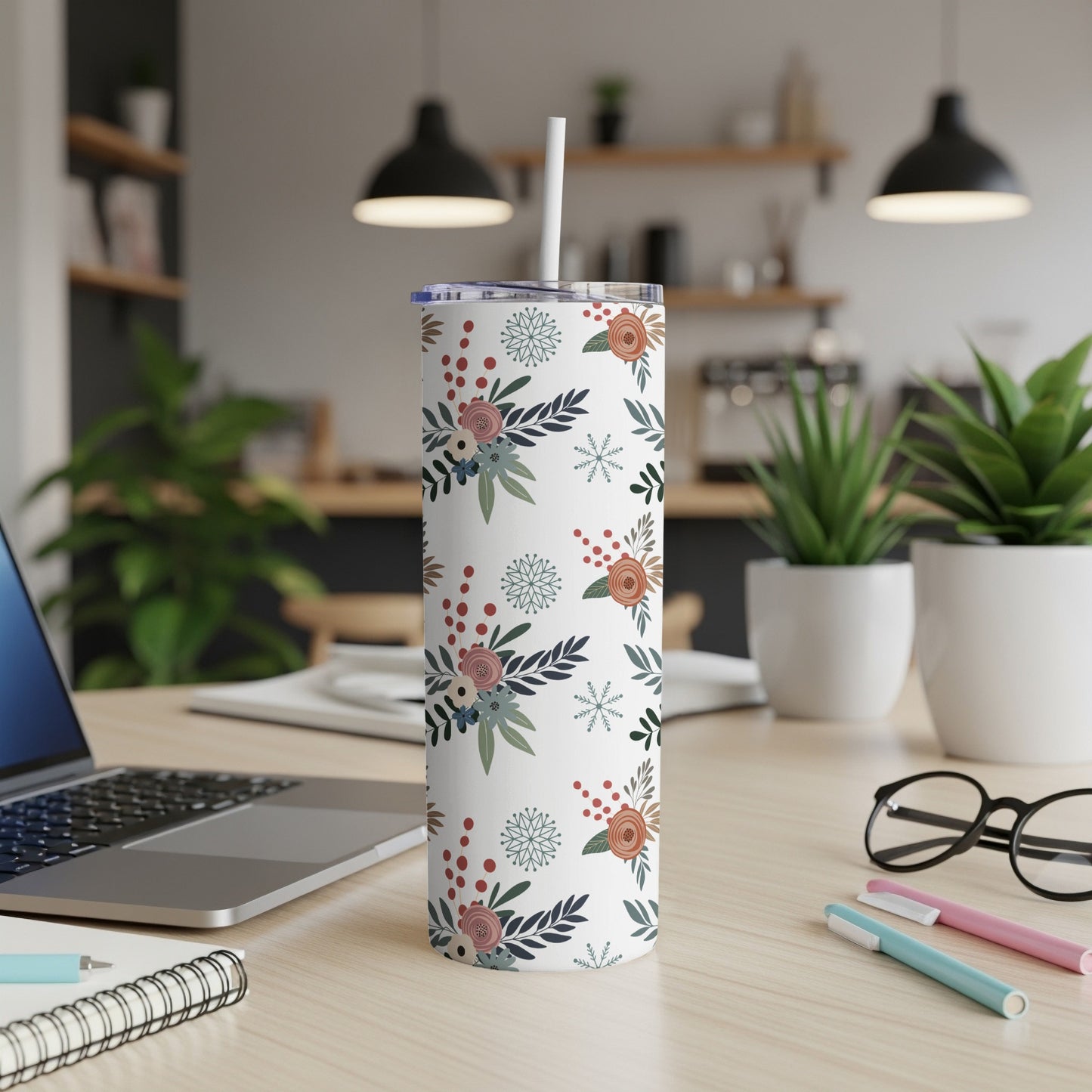 White tumbler with blue snowflakes and floral pattern, straw inserted.