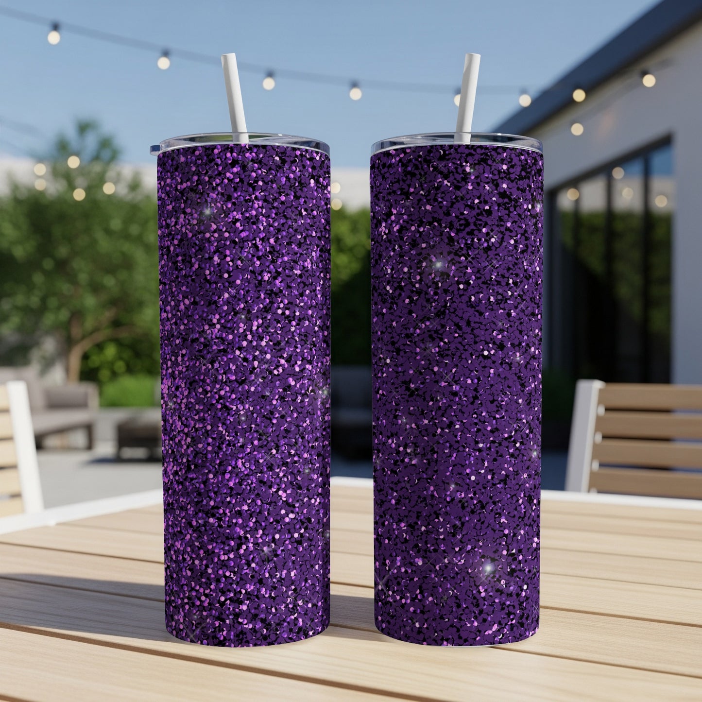 Two purple glitter tumblers with straws on a wooden table outdoors.