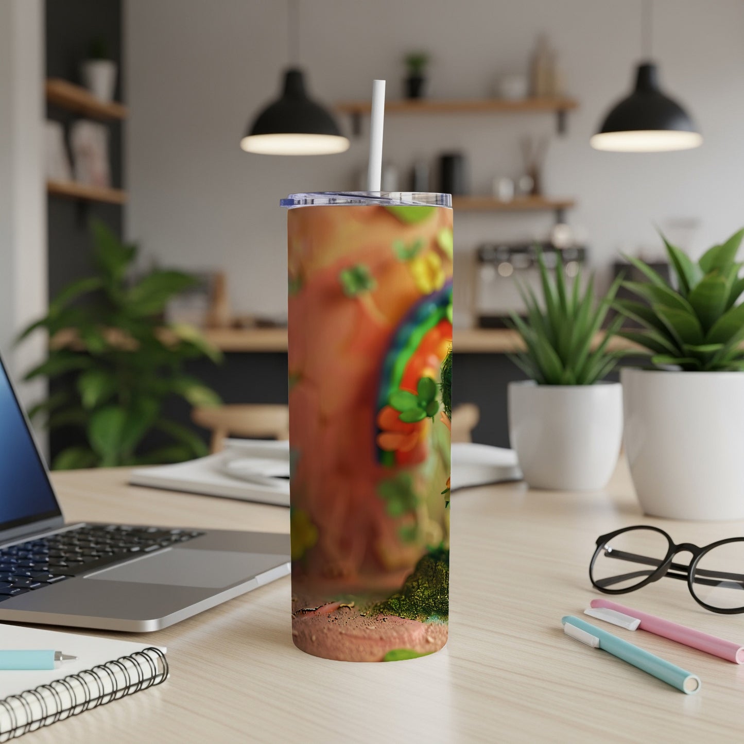 Tumbler with shamrocks and rainbow pattern, shown on a desk.