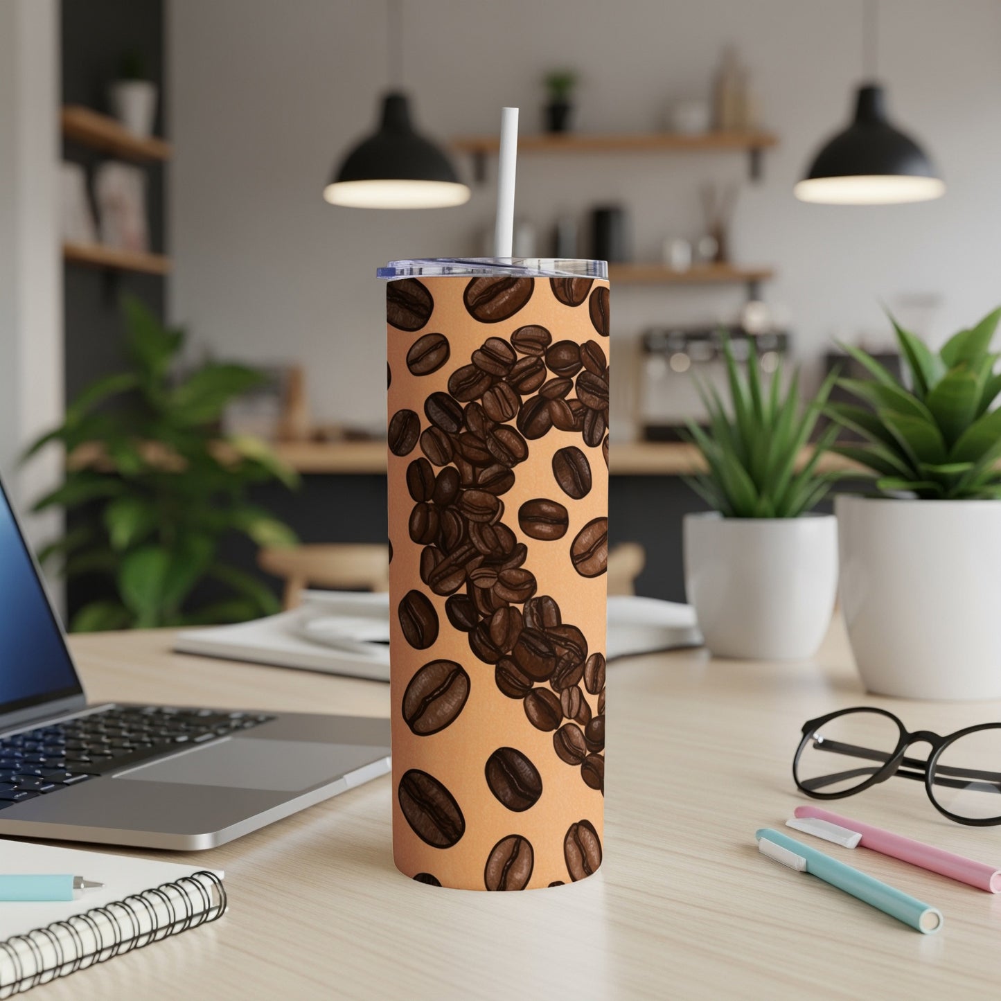 Tall, light brown tumbler with scattered dark coffee beans, on a desk.