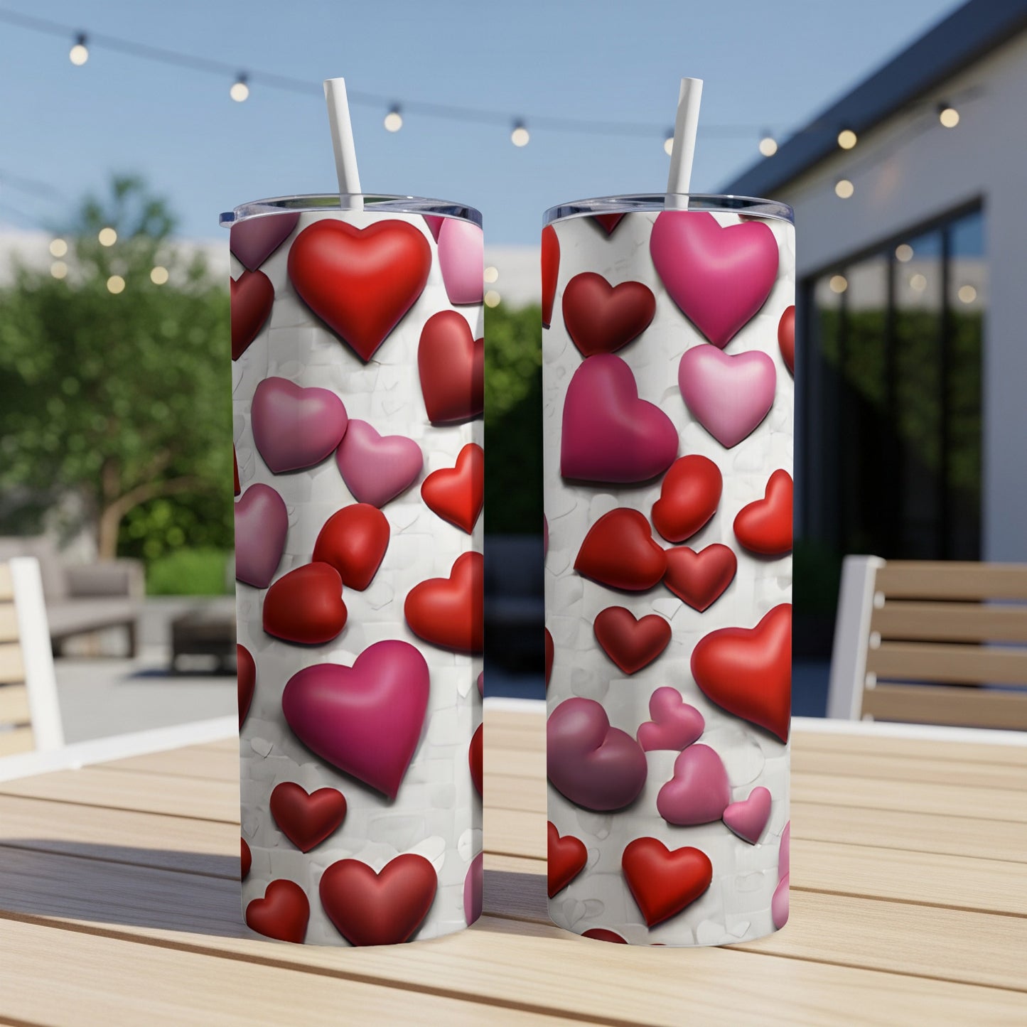 Two insulated tumblers with a scattered heart pattern on a wooden table.