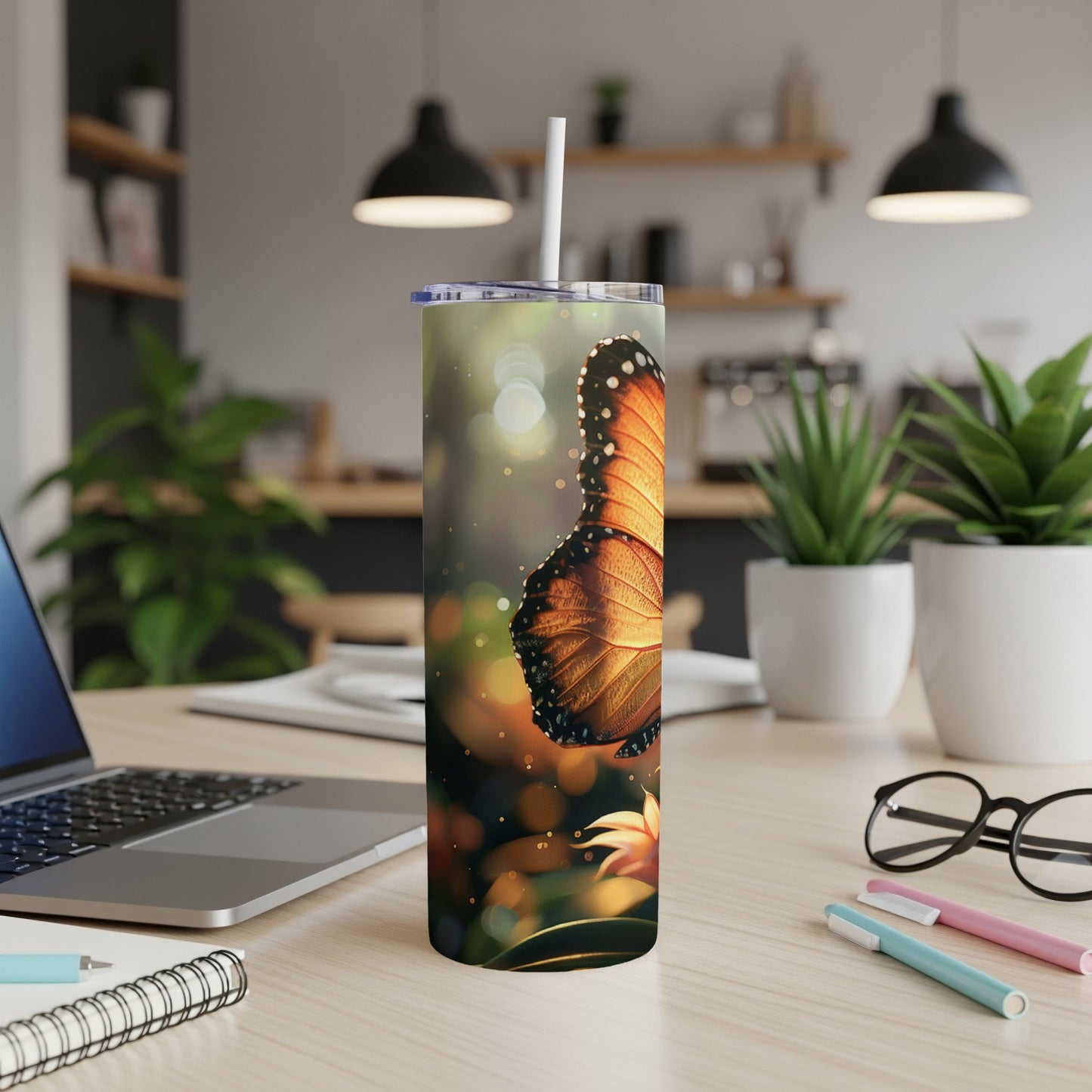 Monarch butterfly on a tumbler with a straw, on a desk.