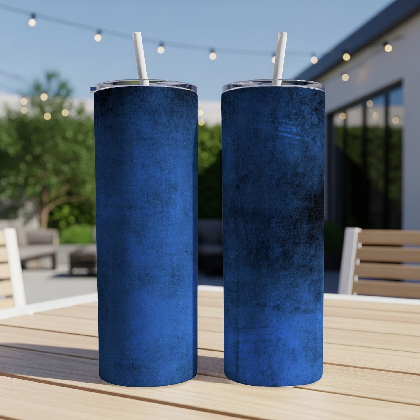Two blue distressed-texture tumblers with white straws and lids on a wooden table.