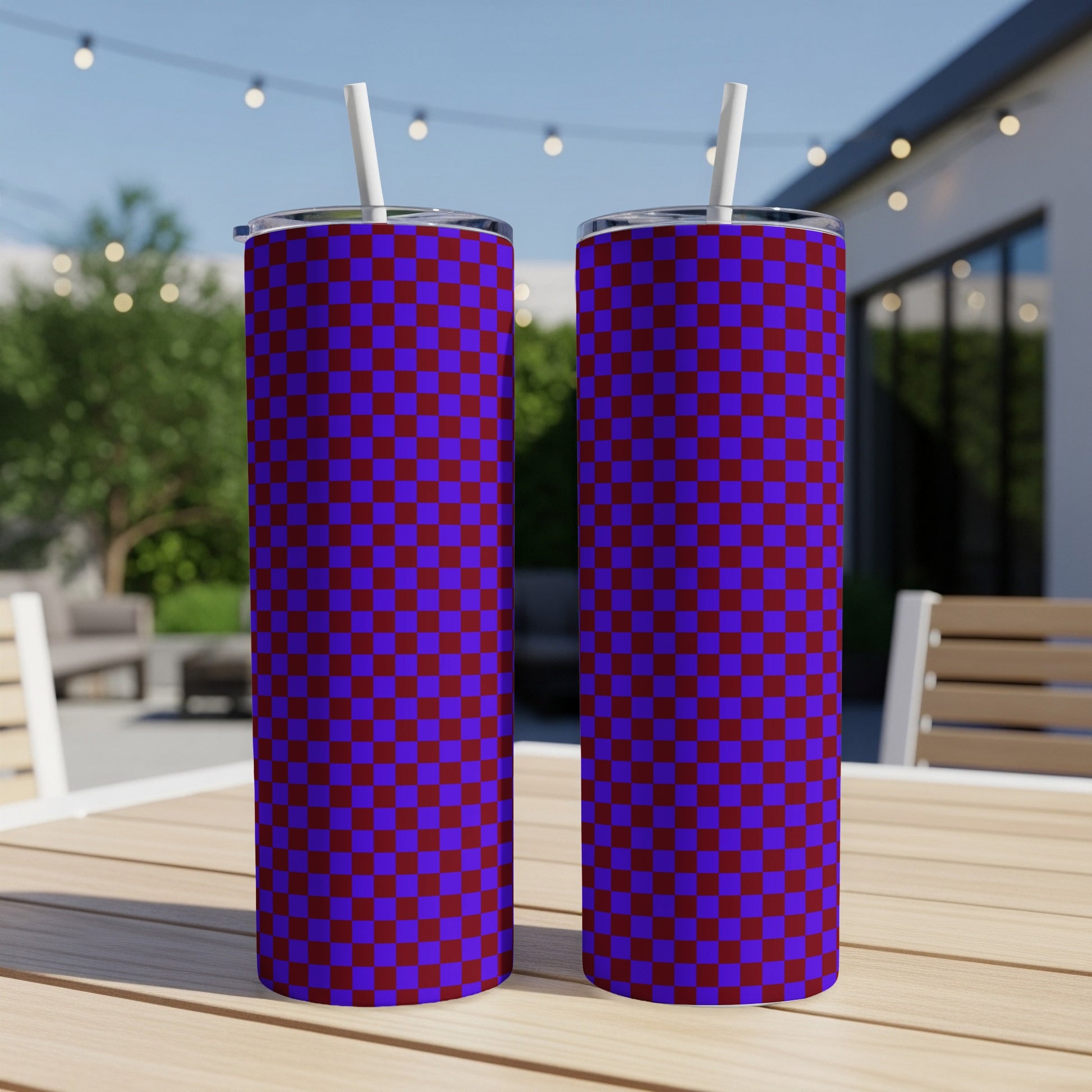 Two purple and red checkered pattern tumblers with straws on a wooden table.
