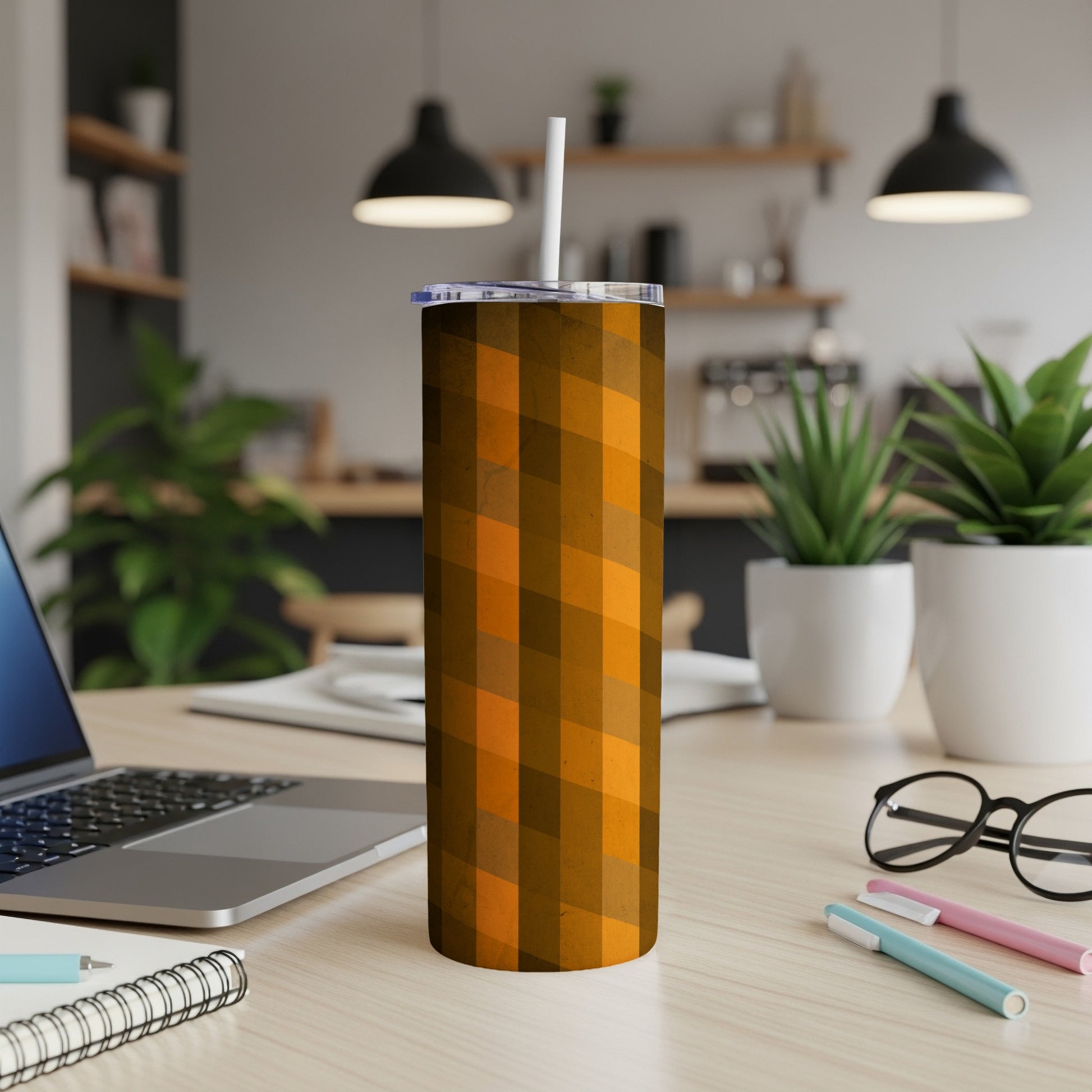 Orange geometric patterned tumbler with straw on a desk.