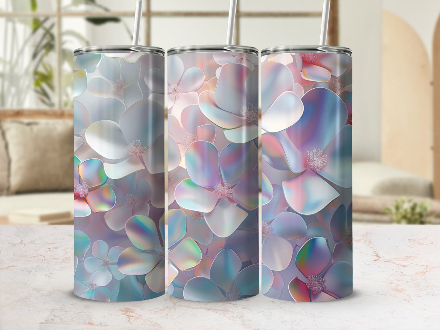 Three iridescent floral tumblers with straws on a marble countertop.