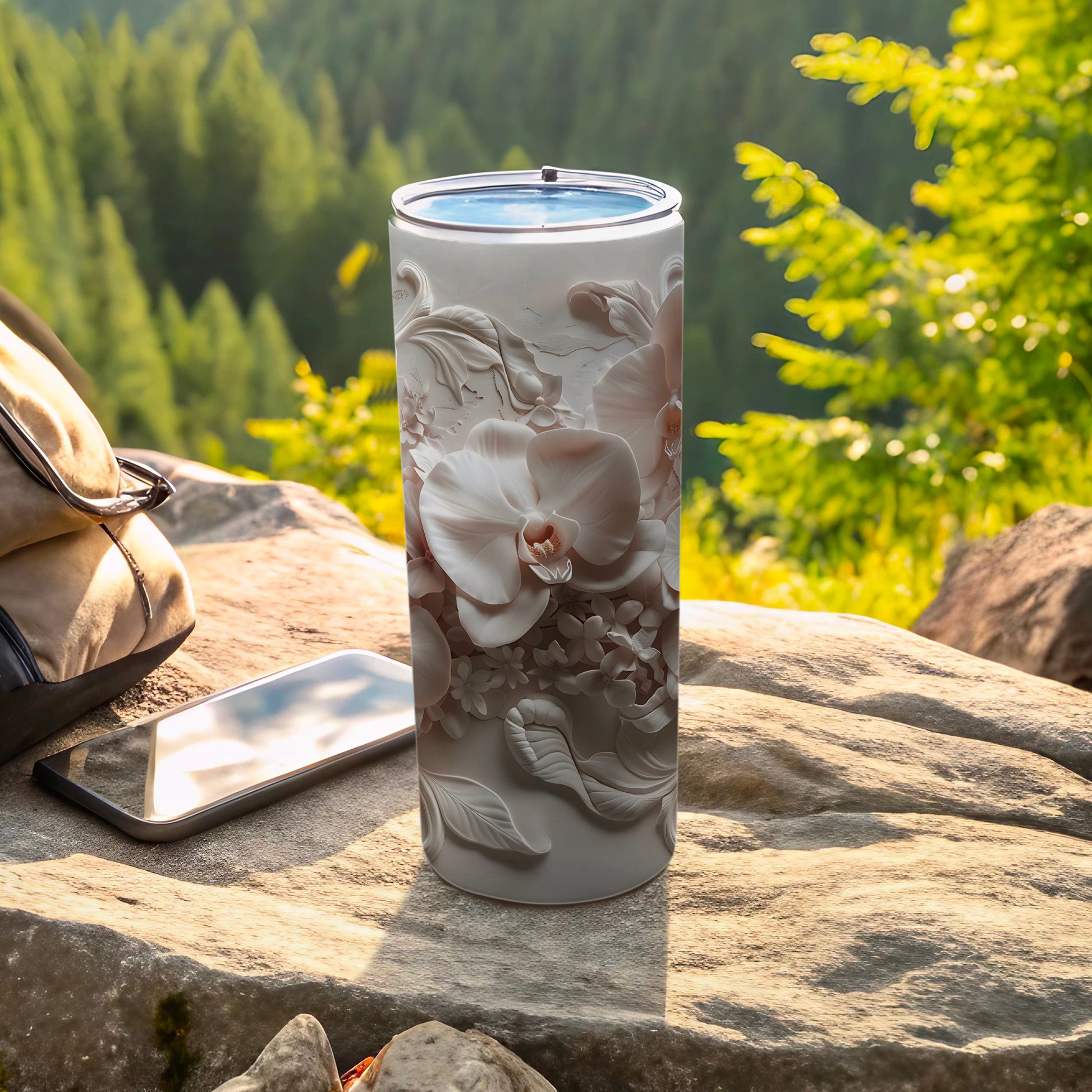 White tumbler with floral embossed design, next to a phone and bag outdoors.