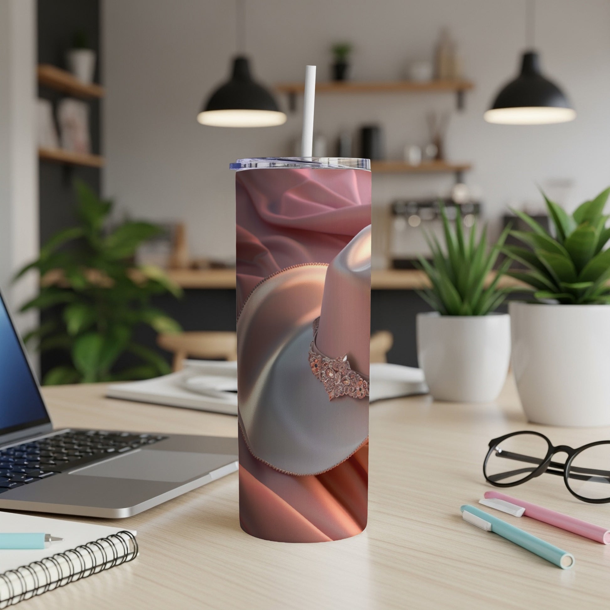 Rose gold tumbler with coffee cup and saucer on a desk.