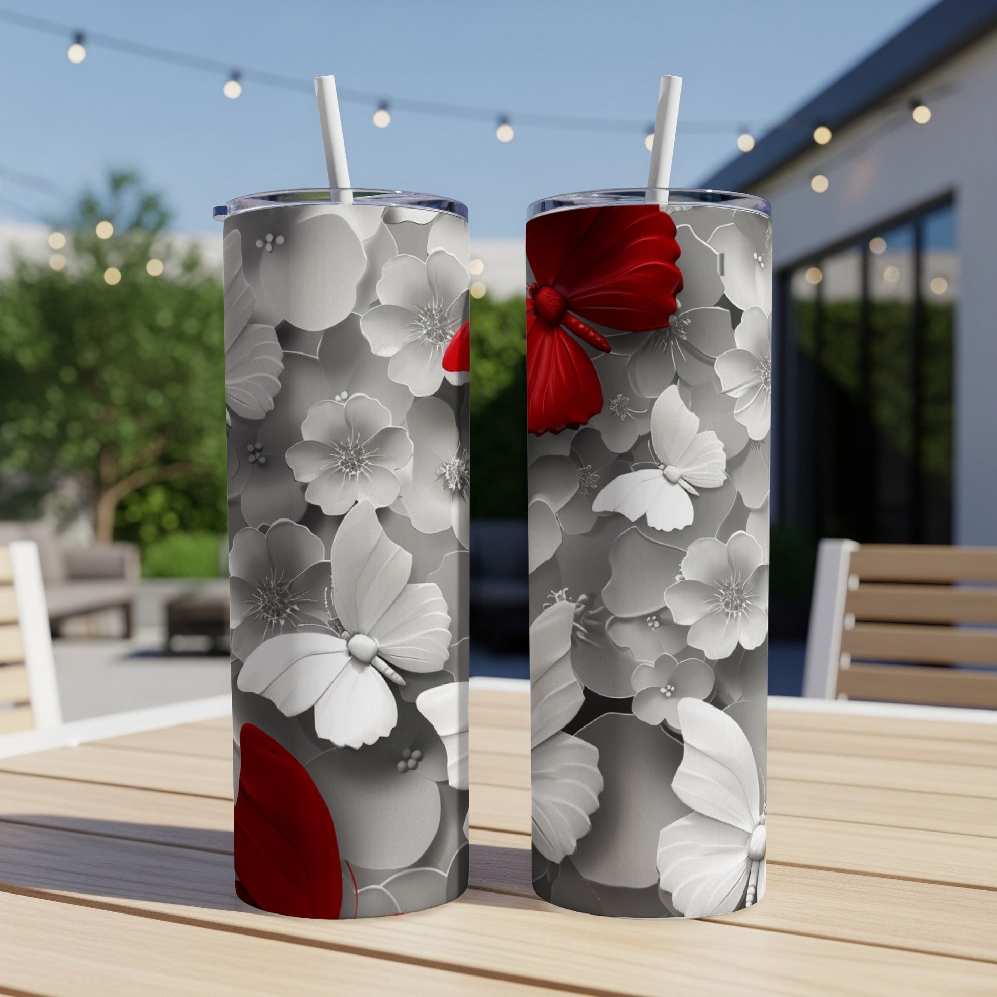Two tumblers with white floral designs and red butterflies on a wooden table.
