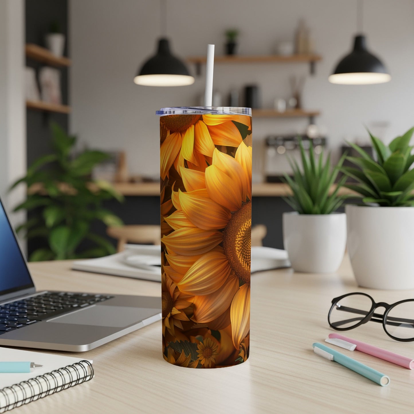 Tall tumbler with sunflower design and straw on a desk.