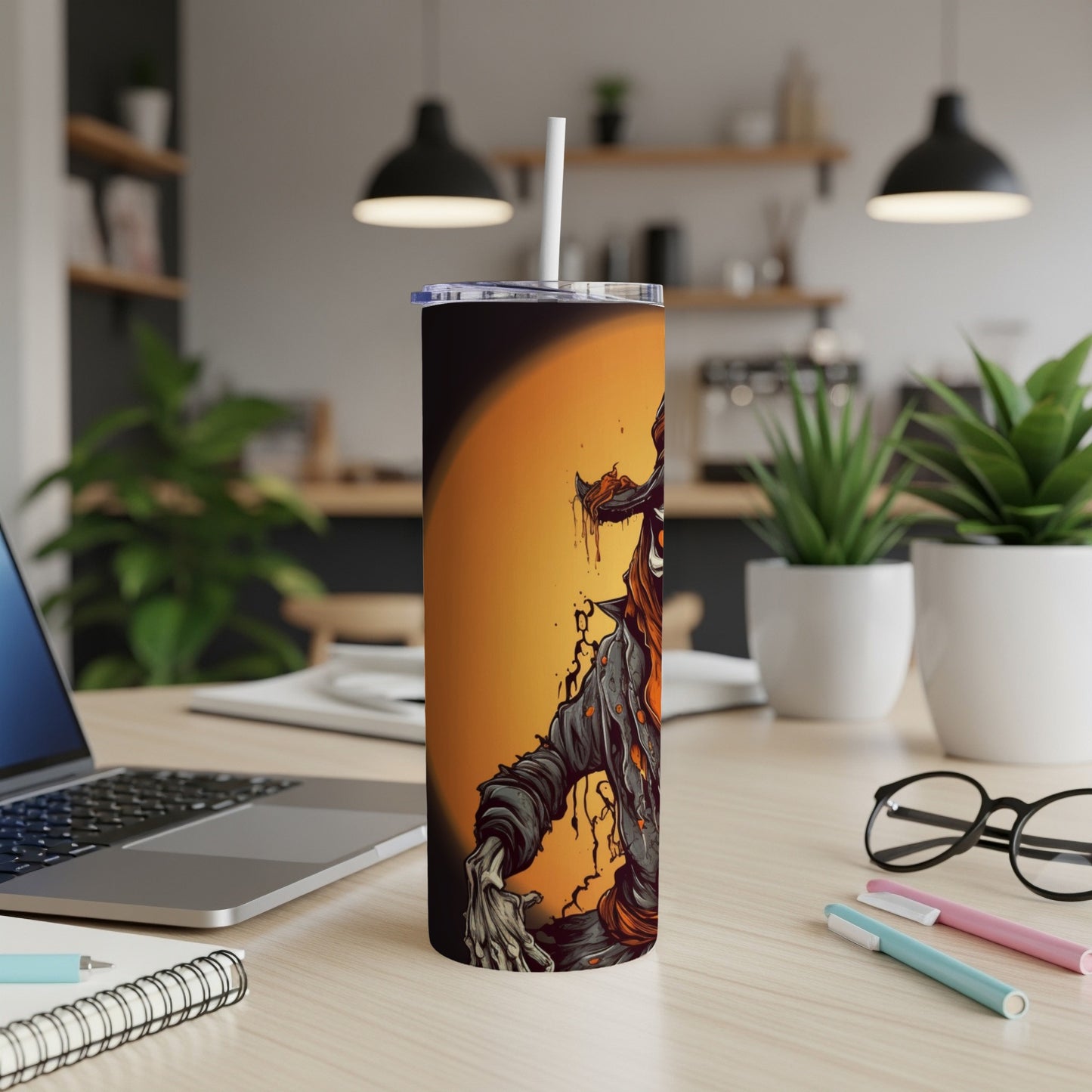Tumbler with scary zombie artwork and straw on a desk.
