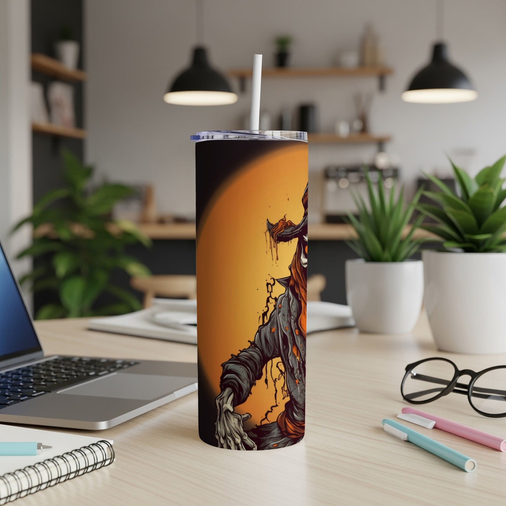 Tumbler with scary zombie artwork and straw on a desk.