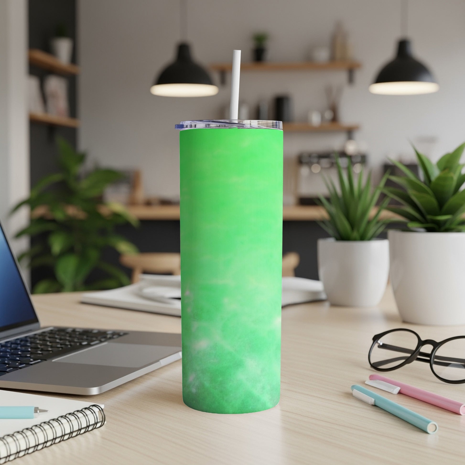 Green marbled tumbler with straw on a wooden desk.