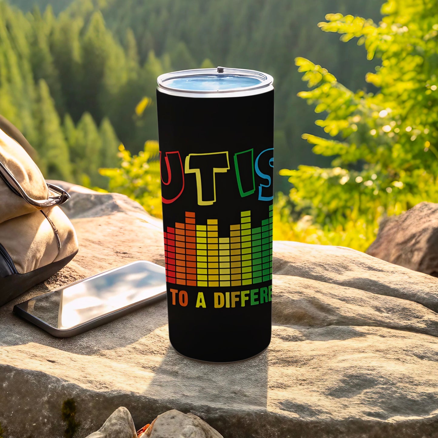 Black tumbler with "AUTISM" in colorful letters and equalizer graphic.