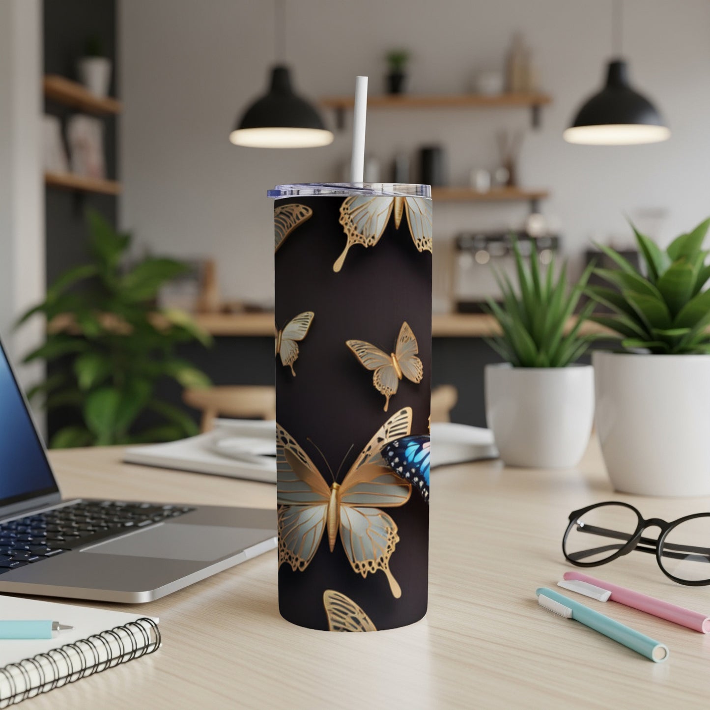 Gold and blue butterflies on a dark tumbler with a straw.