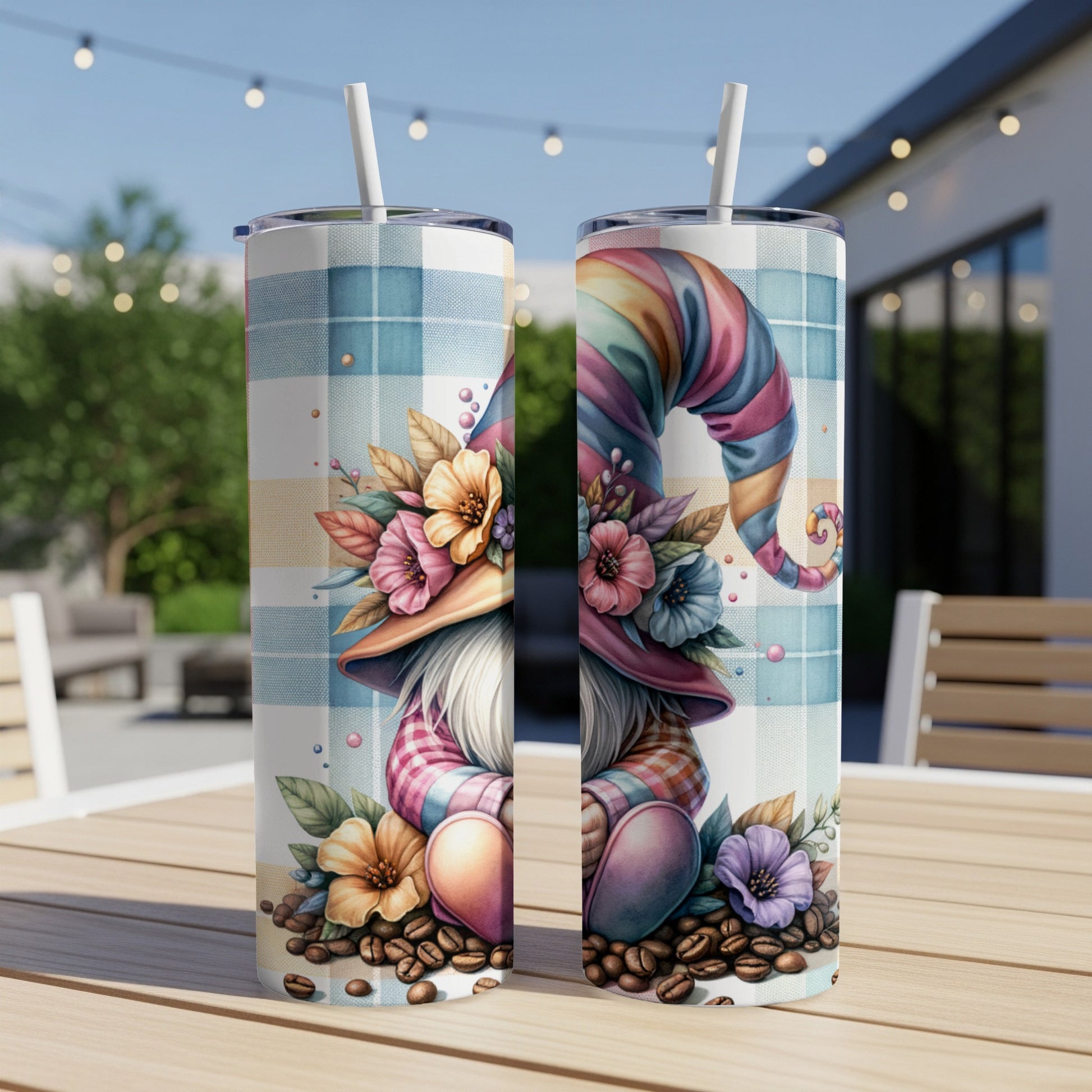 Two gnome tumblers with colorful hats and floral designs sit on a table.