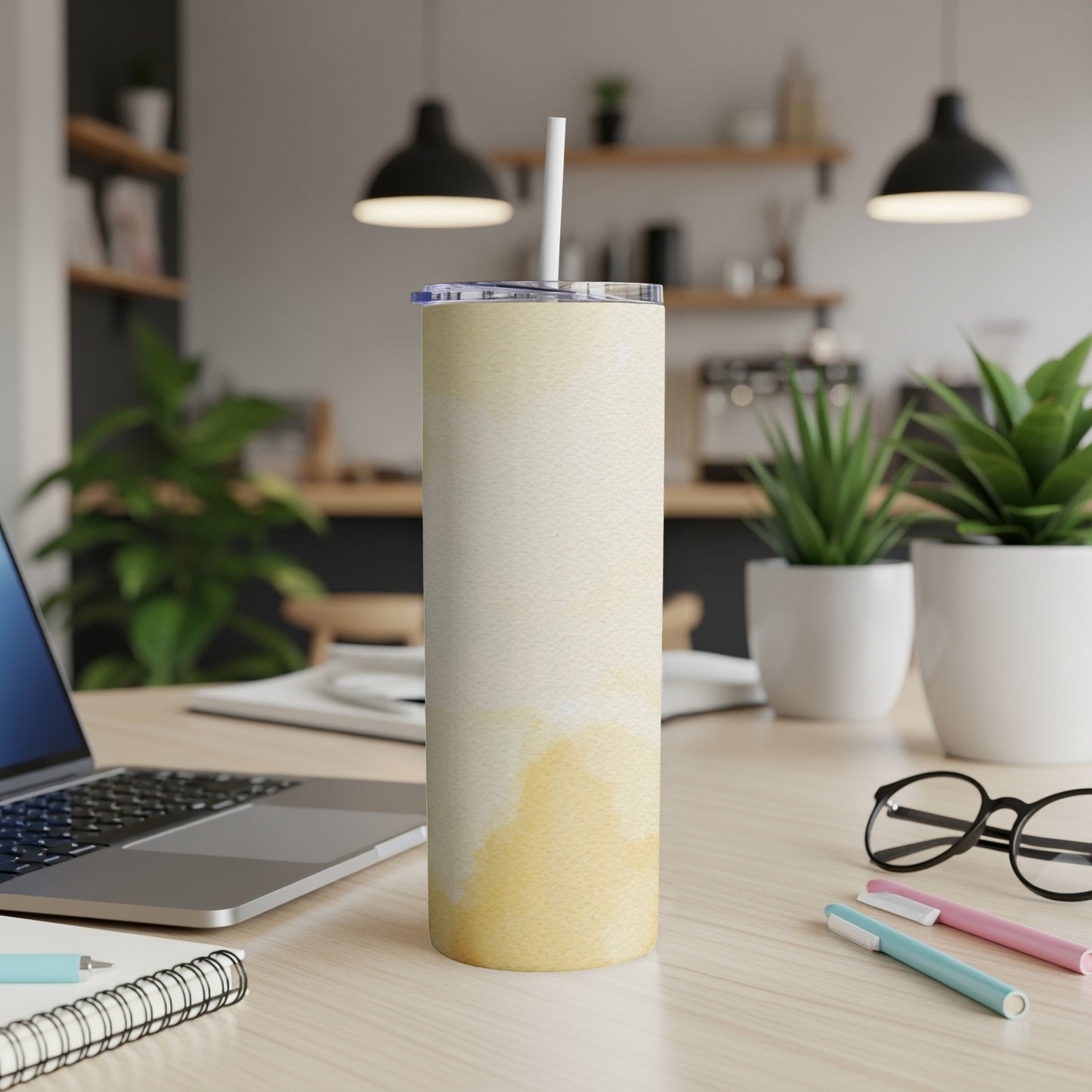 White tumbler with a yellow watercolor design on a wooden desk.
