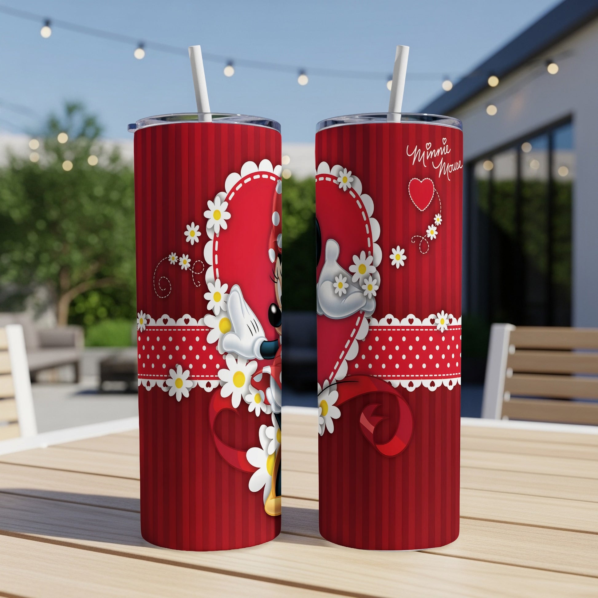 Two red Minnie Mouse heart tumblers with white polka dots and daisies on a table.